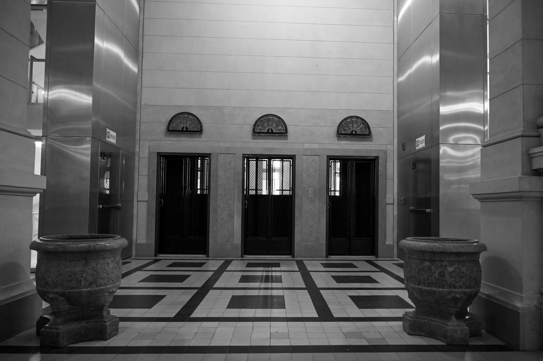 Brass-trim vintage elevator doors in a historic building lobby where cab size and fire-recall rules shape robot routing.