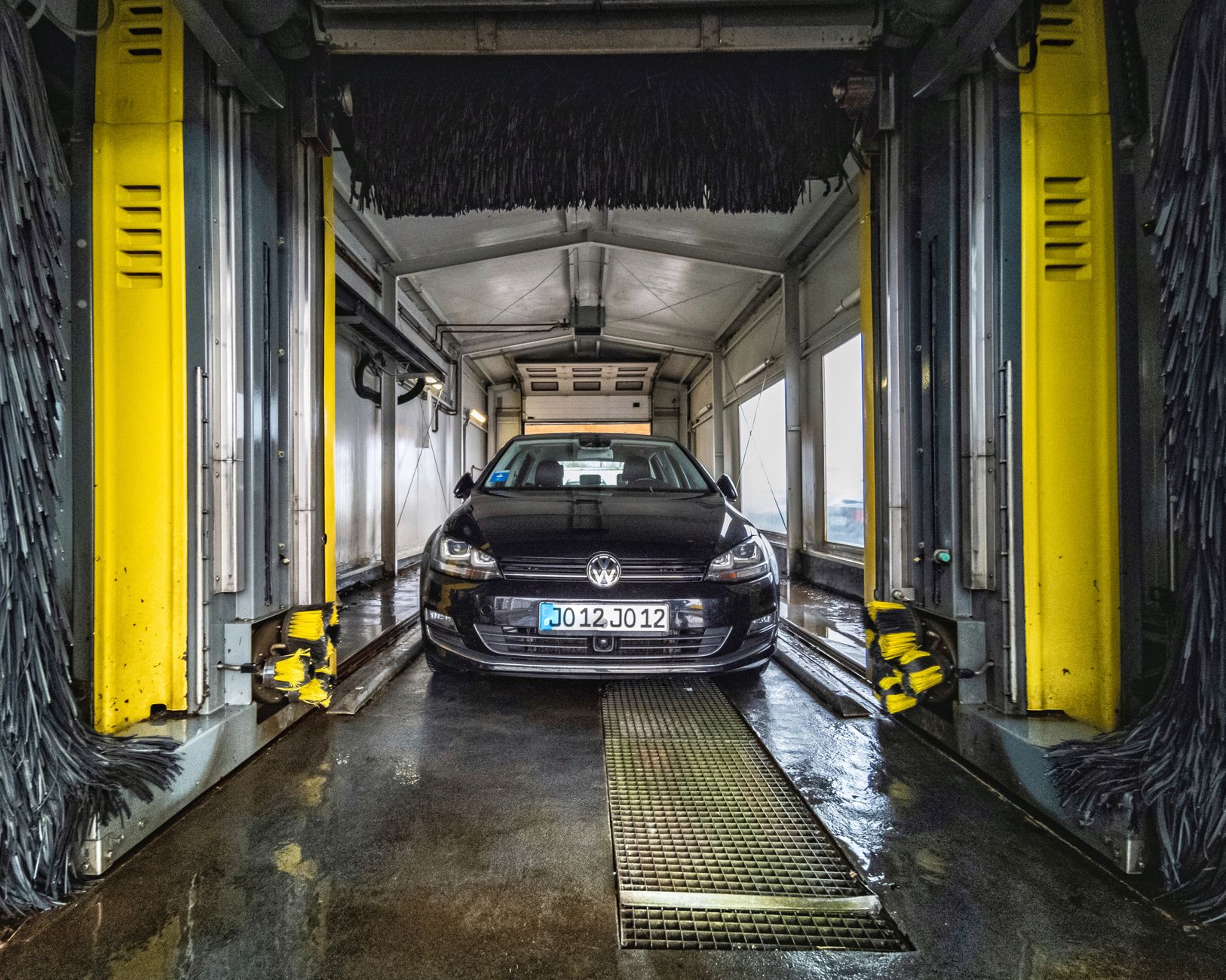 A vehicle is pictured mid-wash, with water spraying its exterior to highlight the automated cleaning process.