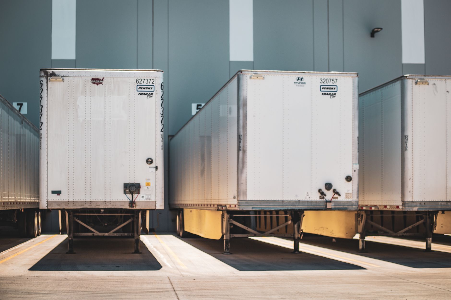 Several semi-trucks parked at the loading dock of a large distribution facility, representing the flow of goods.