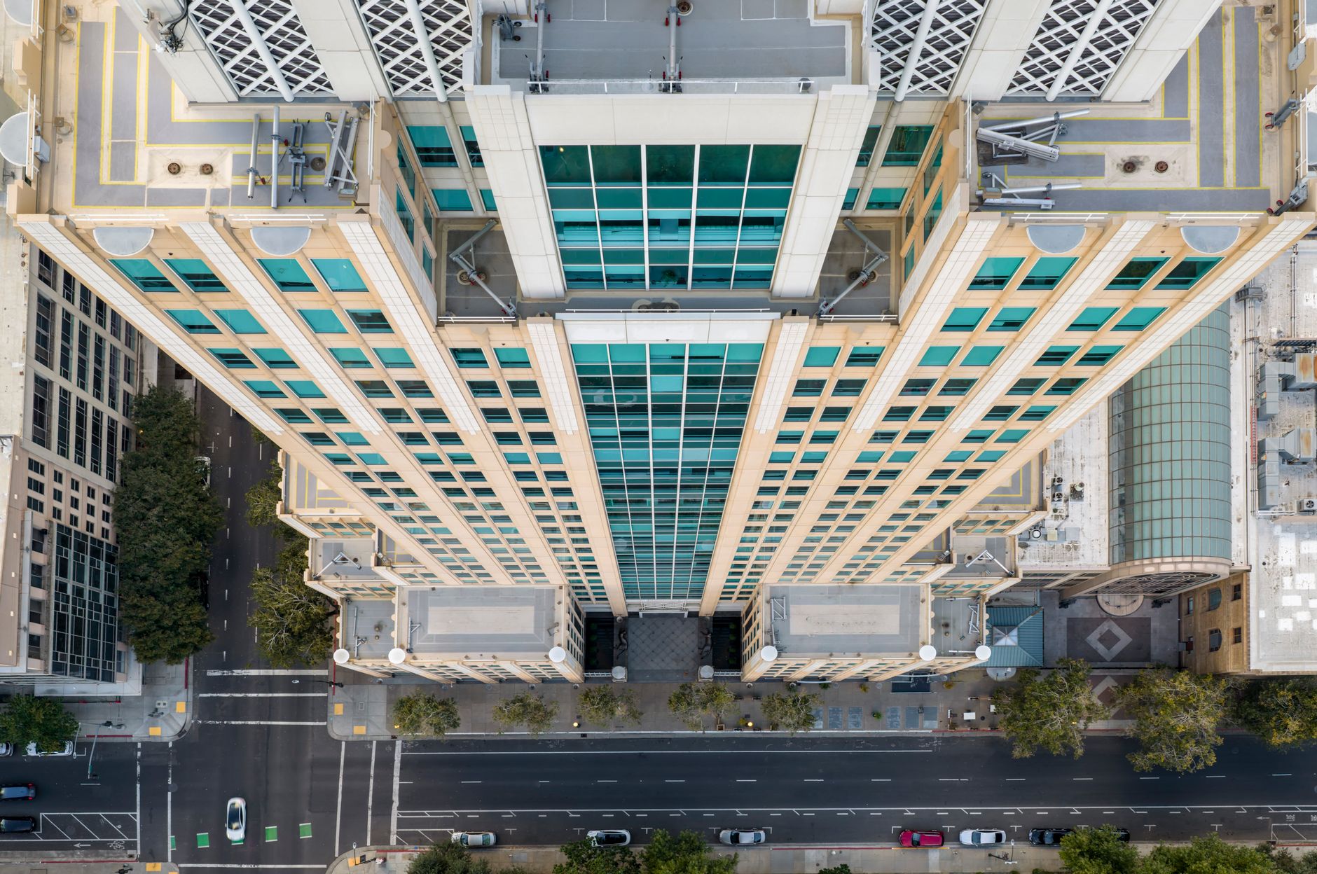 A view from a skyscraper roof looking down the glass exterior of the building, showing the massive vertical surface area to be cleaned.