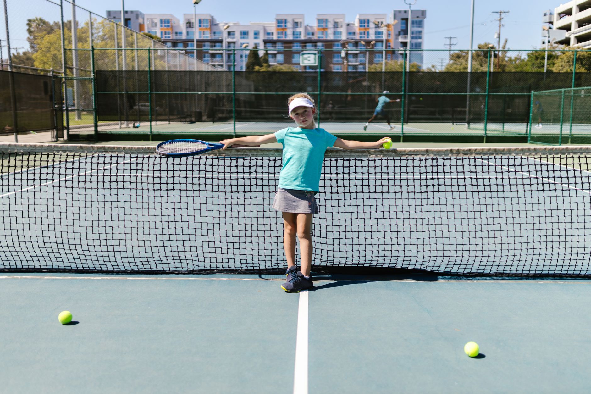 Young players practice among training cones and ball baskets on an indoor tennis court.