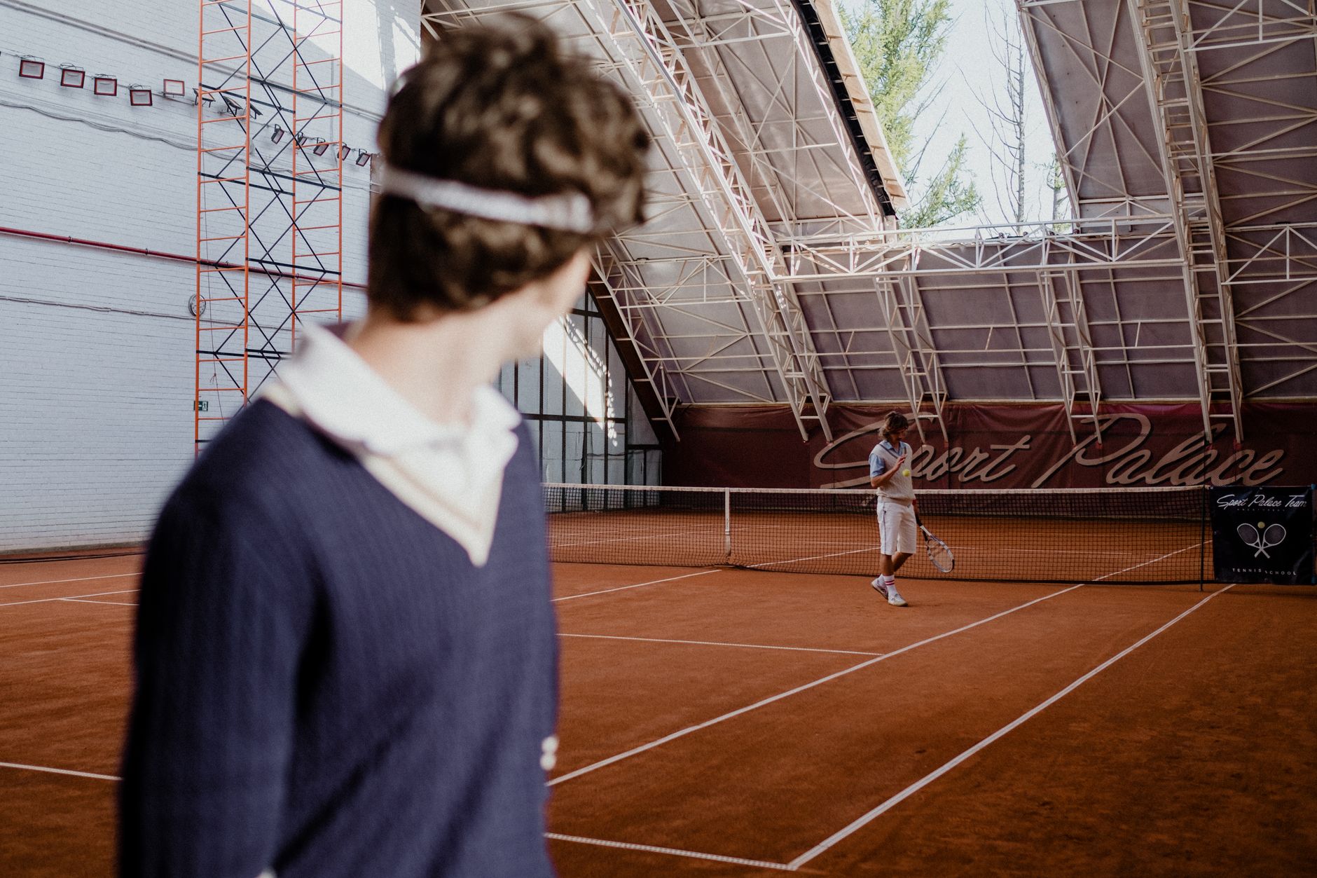 Players practice across several courts inside a busy indoor tennis center.