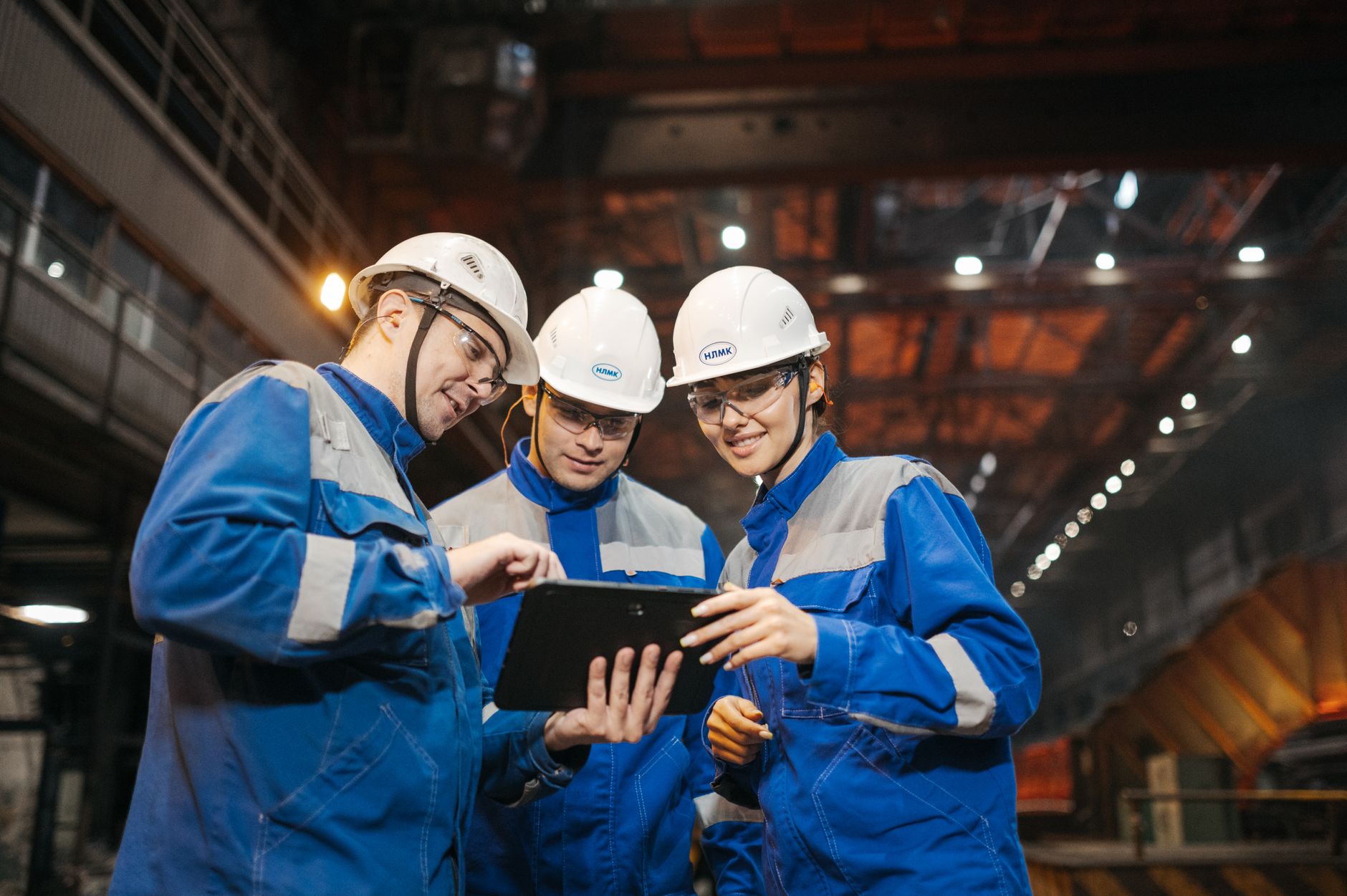 Two engineers review plans on a tablet computer during a site audit inside a large commercial facility.