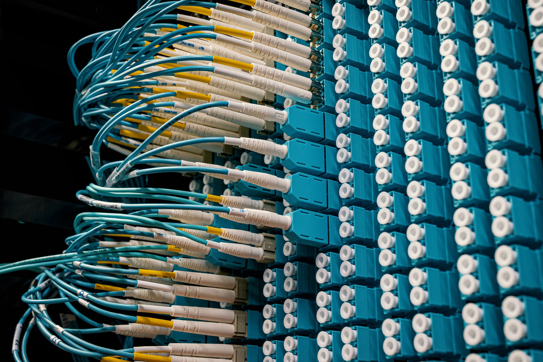 A view down an aisle in a data center with network cables and server racks, illustrating the technical side of system integration.