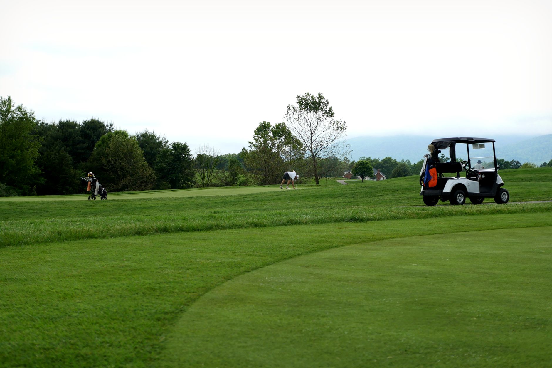 Carts trailing a shared ball across a fairway during alternate-shot league play.