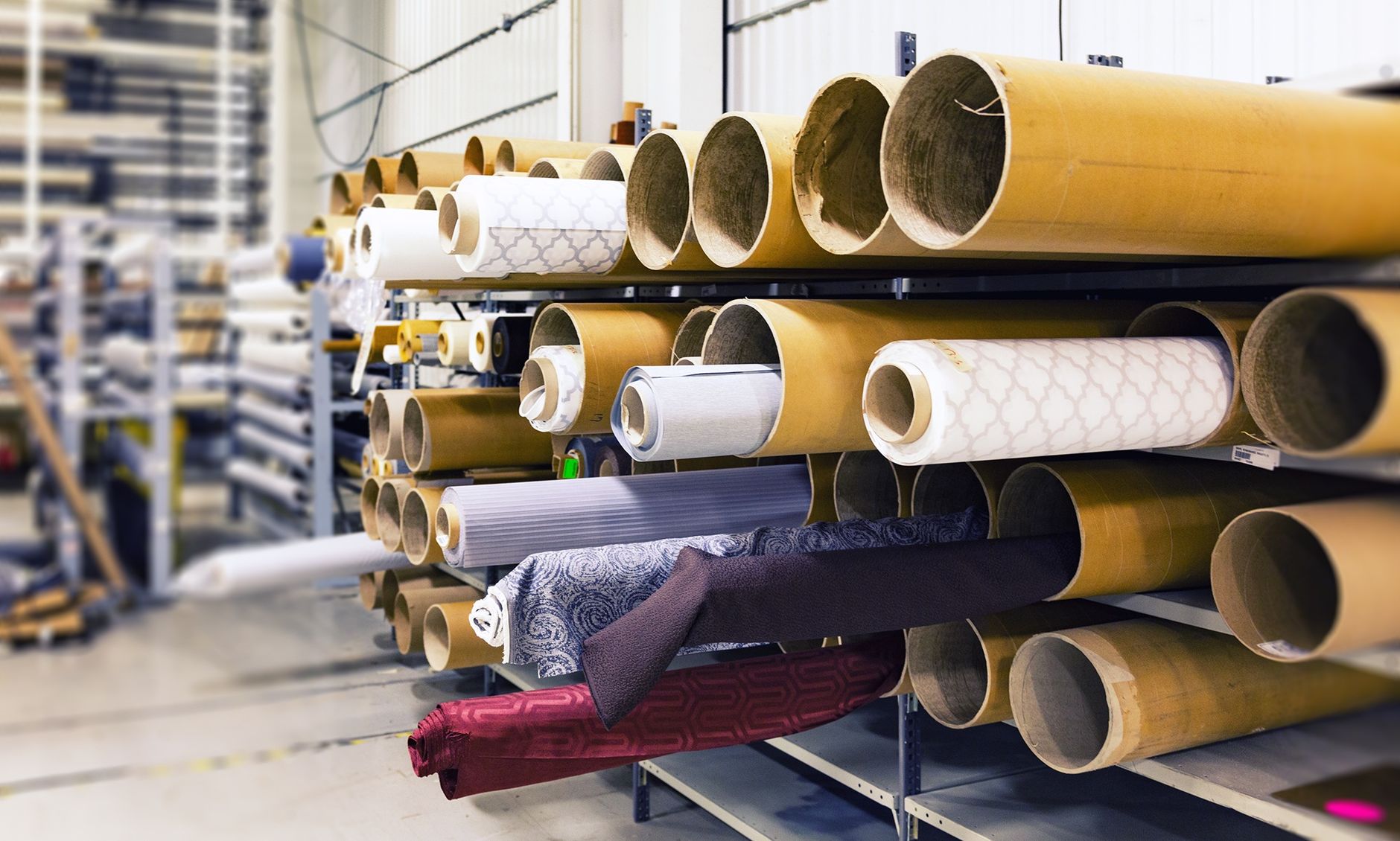 Rows of stored fabric rolls illustrating the changing material volumes behind seasonal route demand.