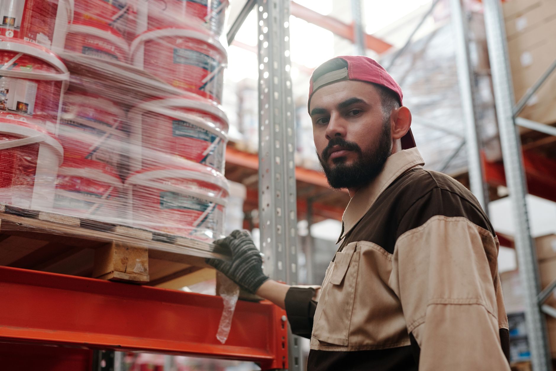 A worker retrieves small parts from organized shelving in an industrial stockroom.