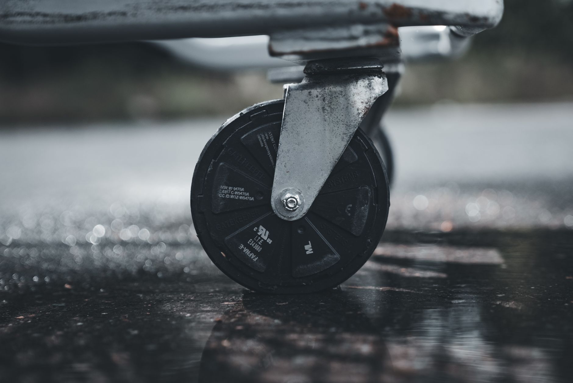 A close view of a caster wheel and lower frame on a commercial rolling rack.