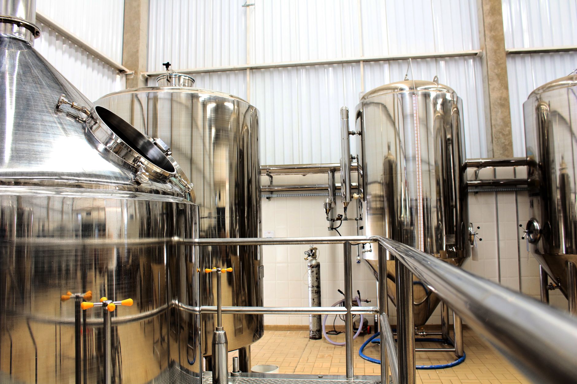 Brewhouse with stainless vessels and wide aisles for keg movement.
