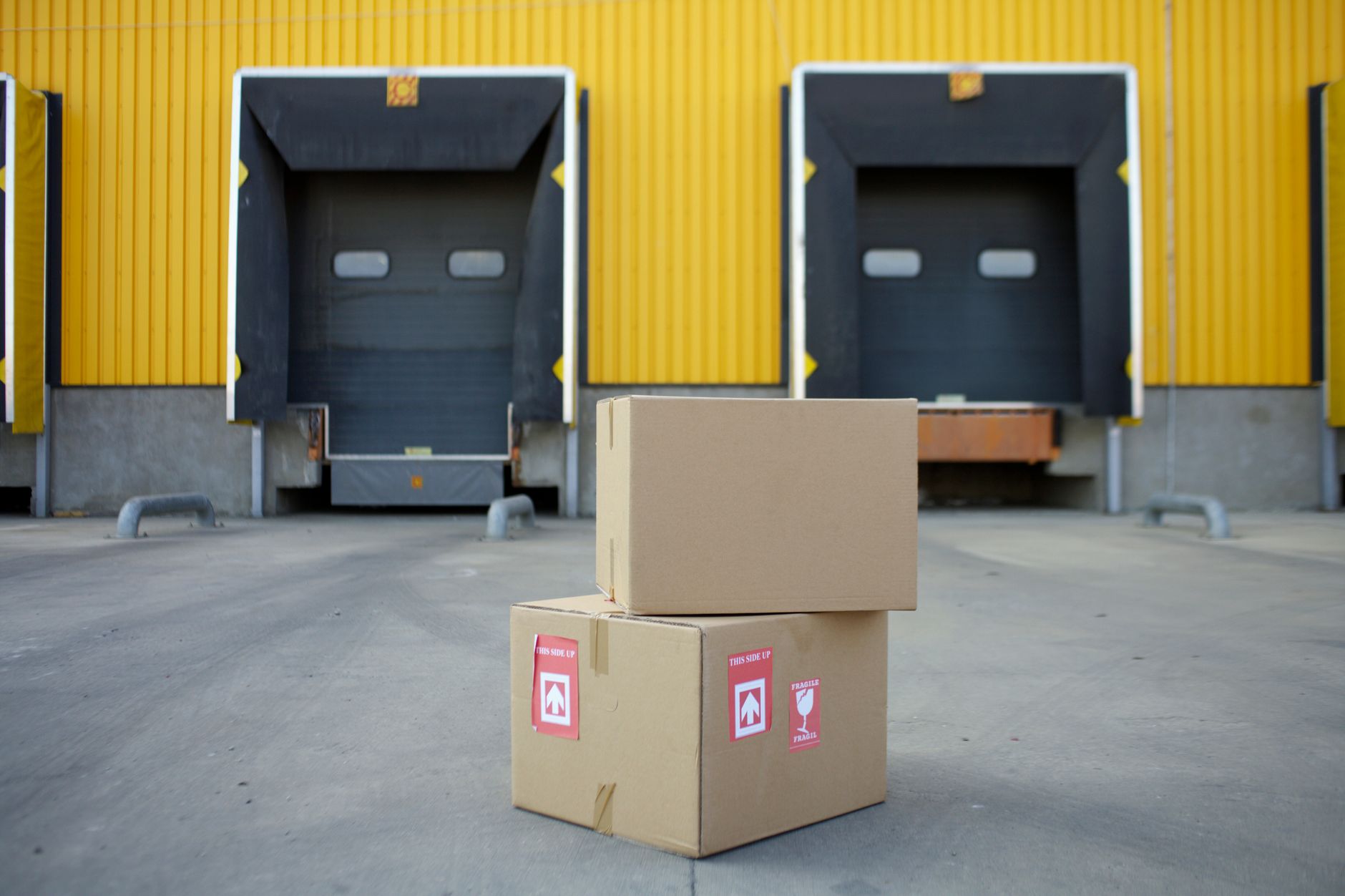 Stacks of boxes at a commercial loading dock, representing the fixed-origin package and supply runs that make strong first AMR routes on campuses.