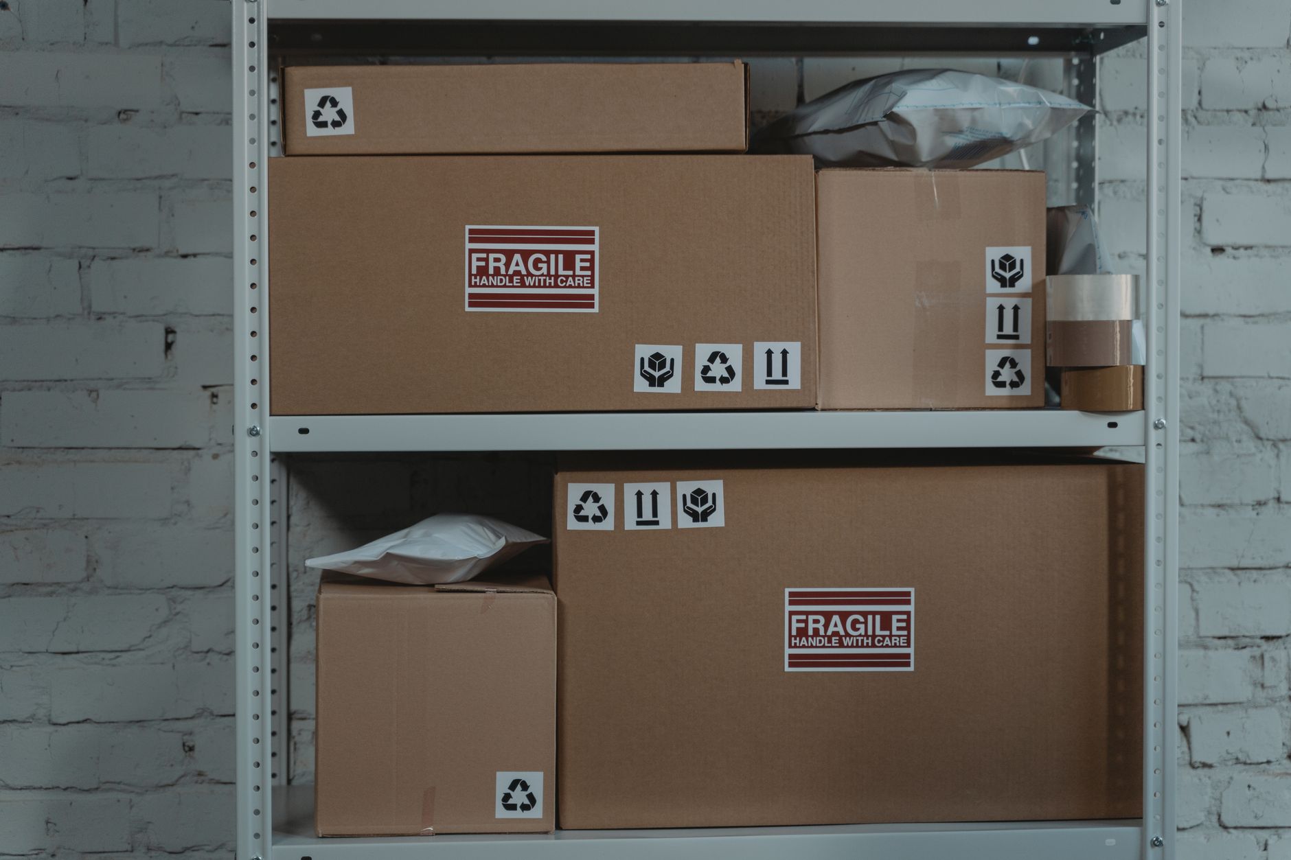 Shelving filled with labeled parcels in a campus-style package room, illustrating the central hub where staff sort deliveries before interbuilding runs.