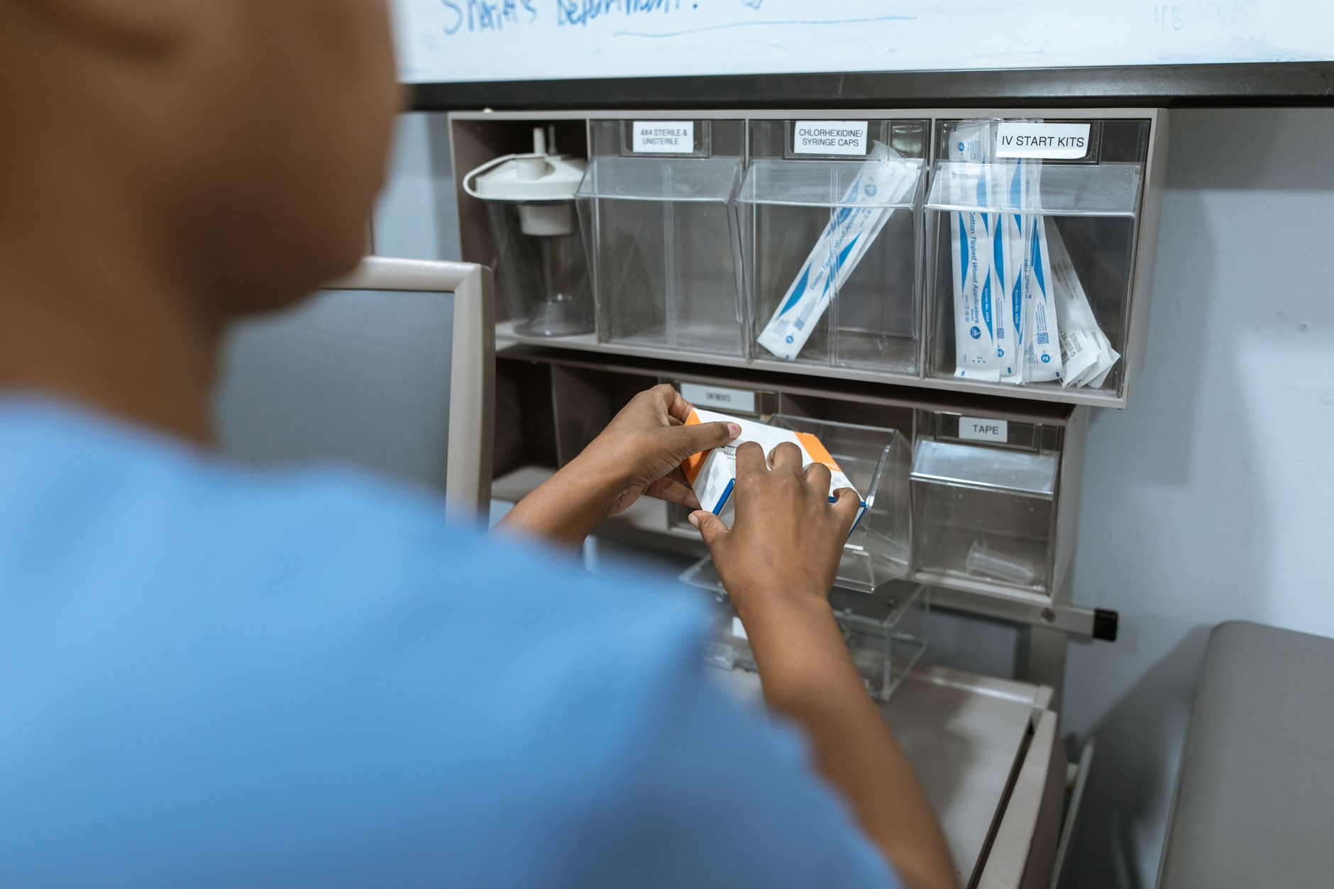 A nurse checks organized clinical supplies inside a hospital stock closet.