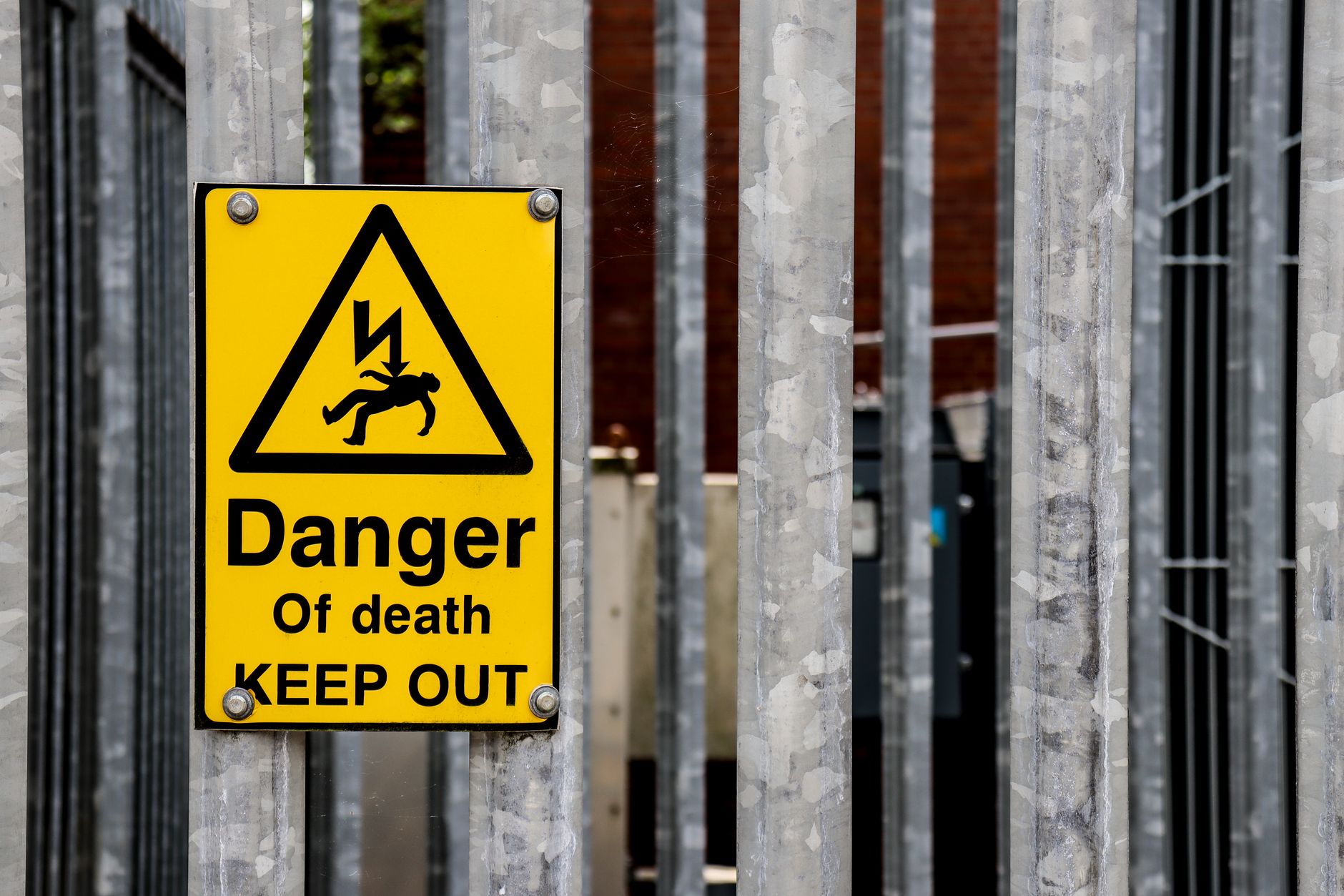 Hazard and restricted-area signs mark a controlled section of an industrial facility.