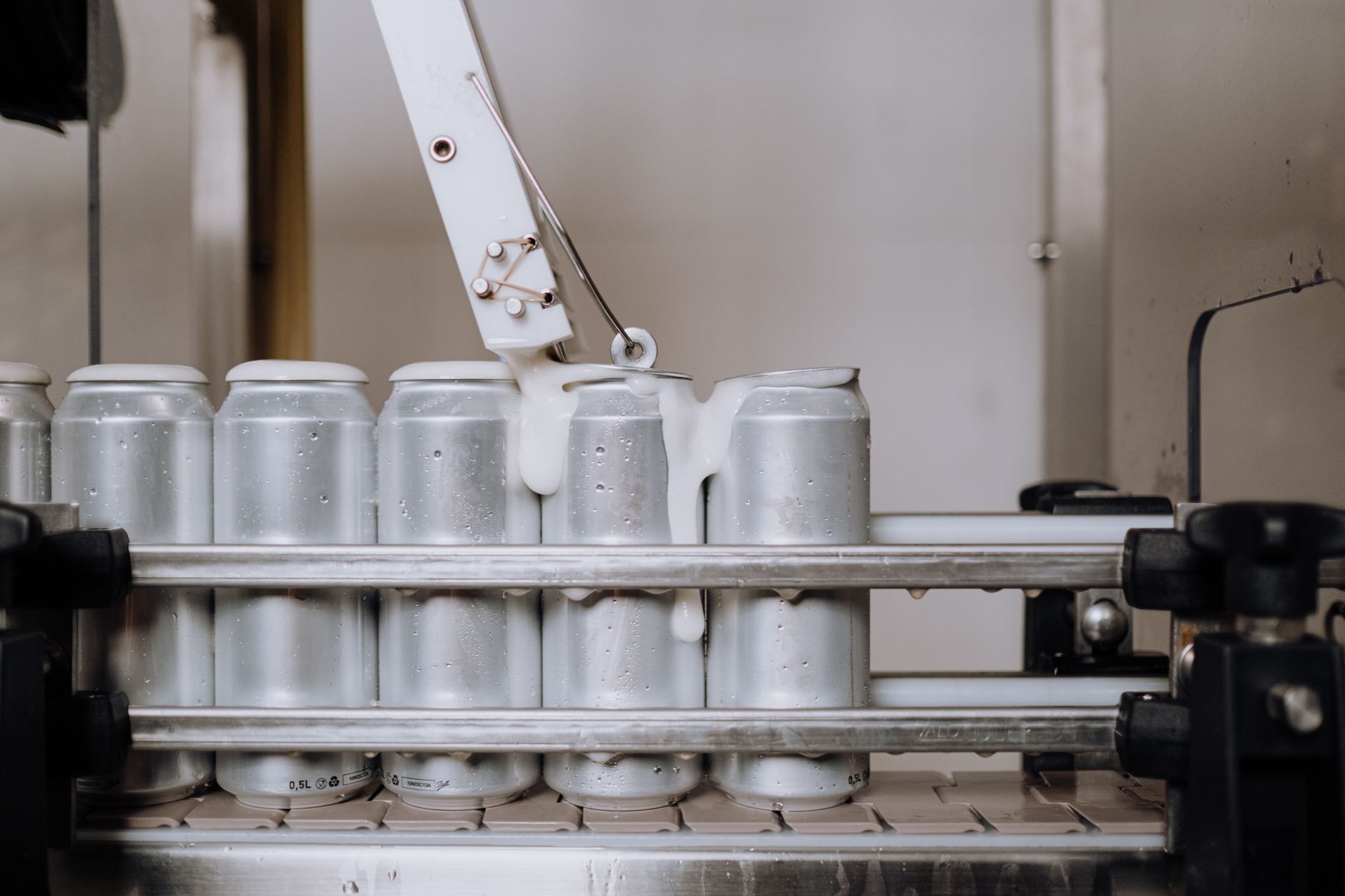 Rows of sealed paint cans and pails staged on a coatings plant floor ready for curing or outbound shipping.
