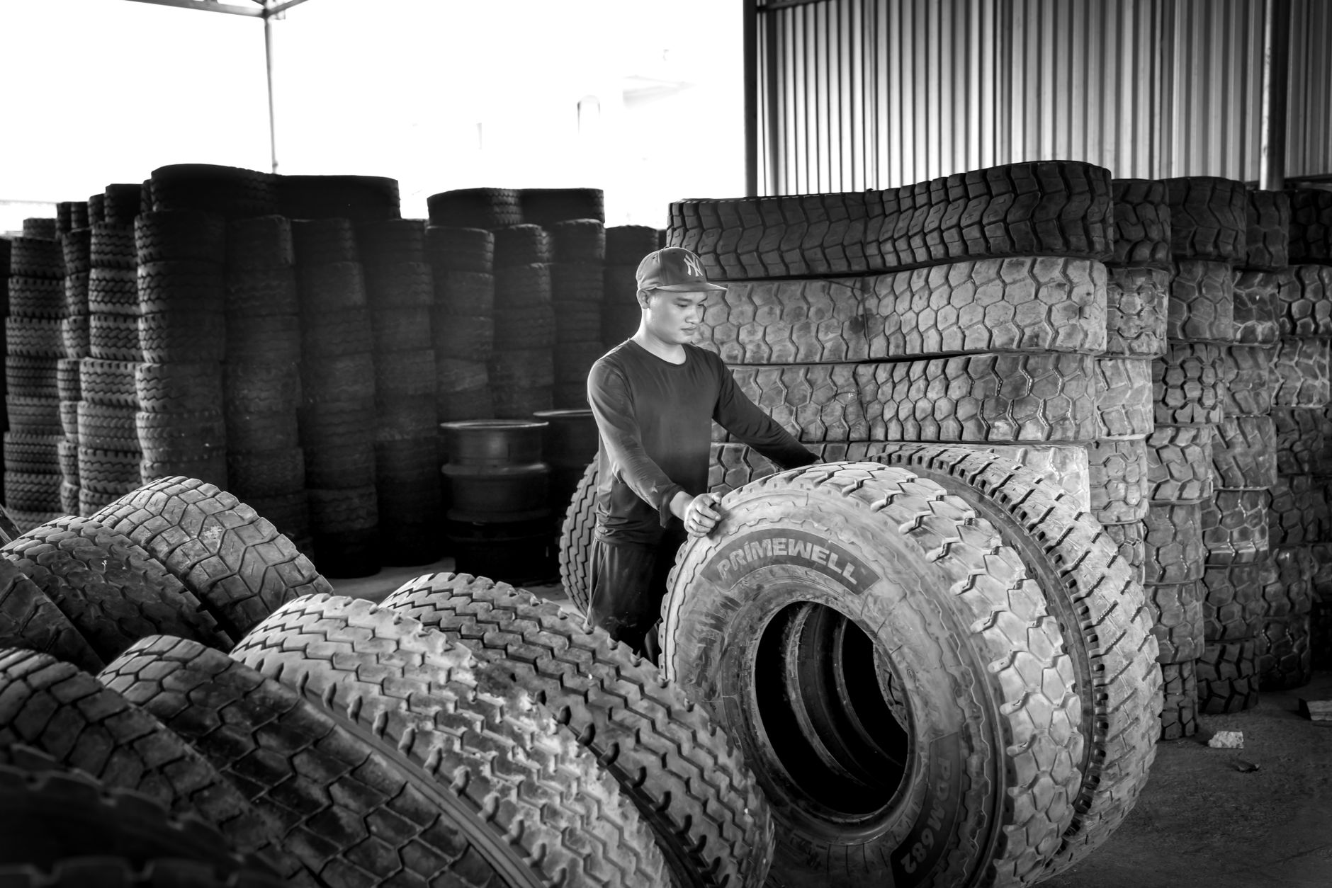 A worker handles tires on the production floor of a tire manufacturing plant.