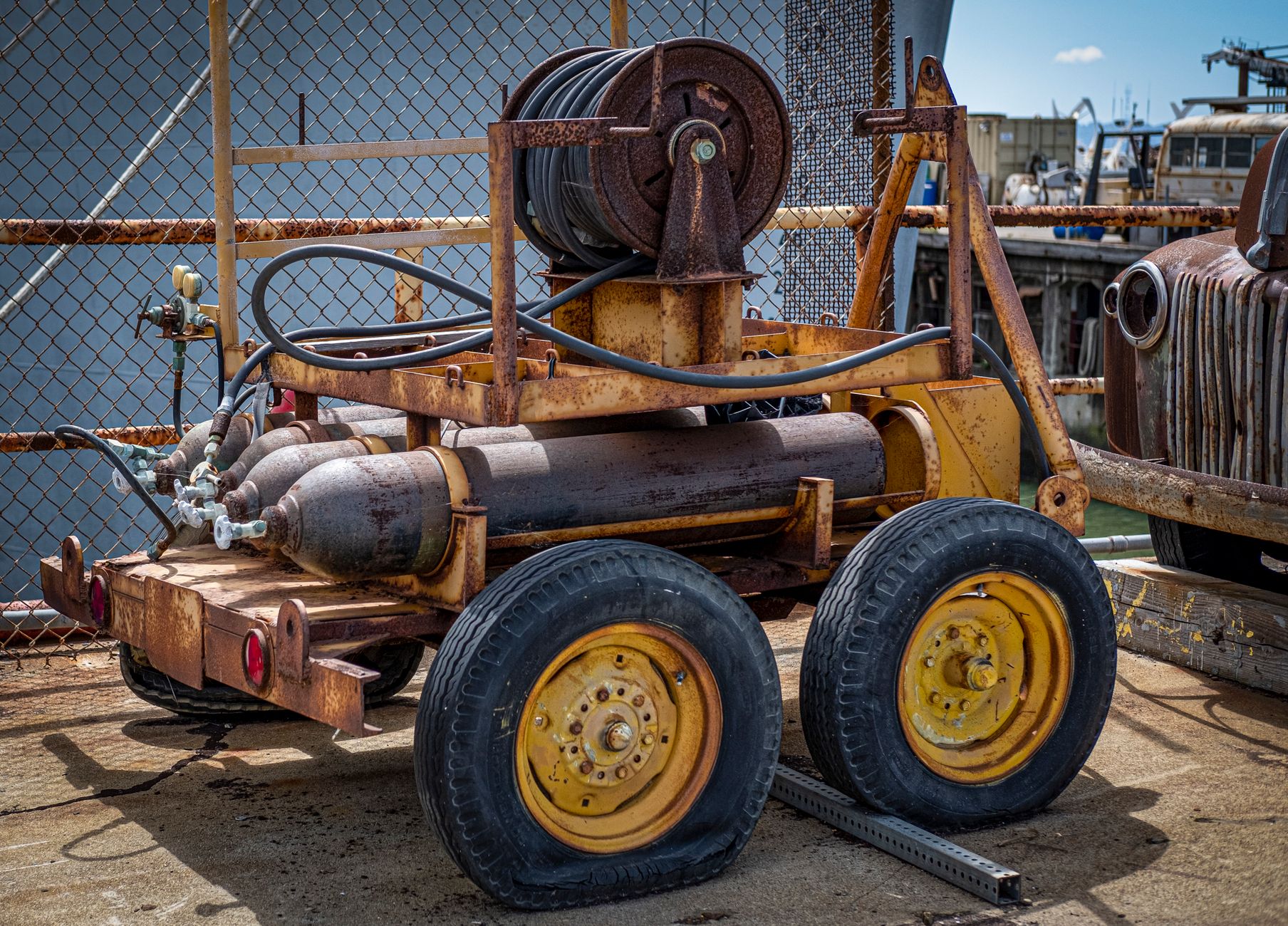 A low industrial cart carries heavy metal tooling across a factory floor toward a work cell.