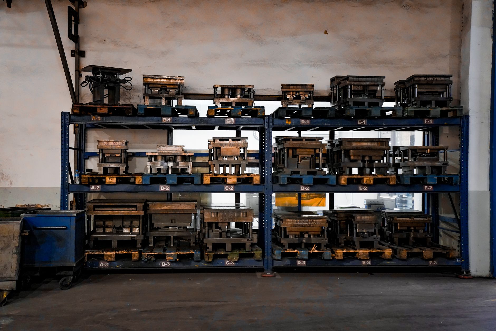 A worker in a metal stamping plant stands beside a large press used for heavy die work.