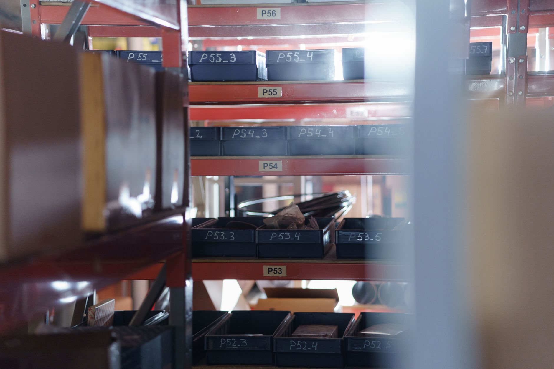 Standardized bins and totes staged beside a production area, matching the repetitive parts-delivery loops that make strong first AMR candidates.