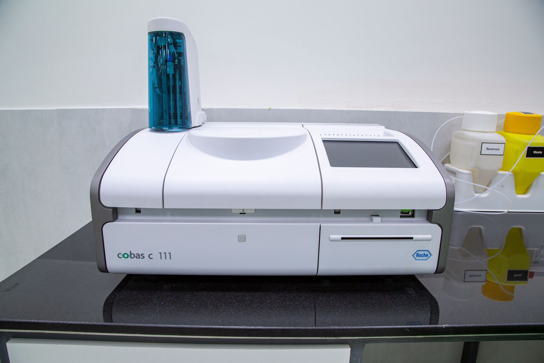 A pathology professional handling labeled glass slides at a hospital laboratory workstation.