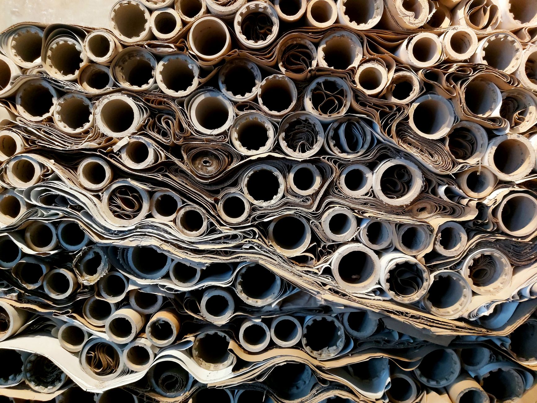 Large paper and film rolls stored vertically in a narrow warehouse aisle.