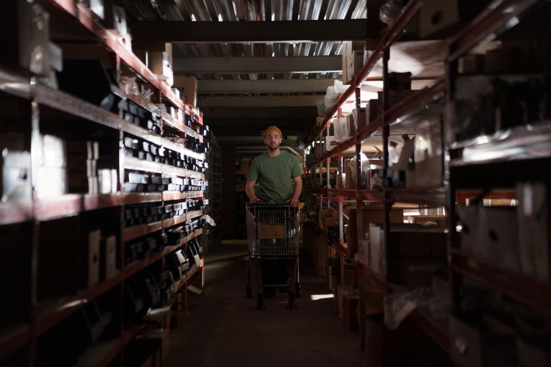 A warehouse worker pushing a loaded cart through a tight aisle, showing the physical strain and congestion described in returns zones.