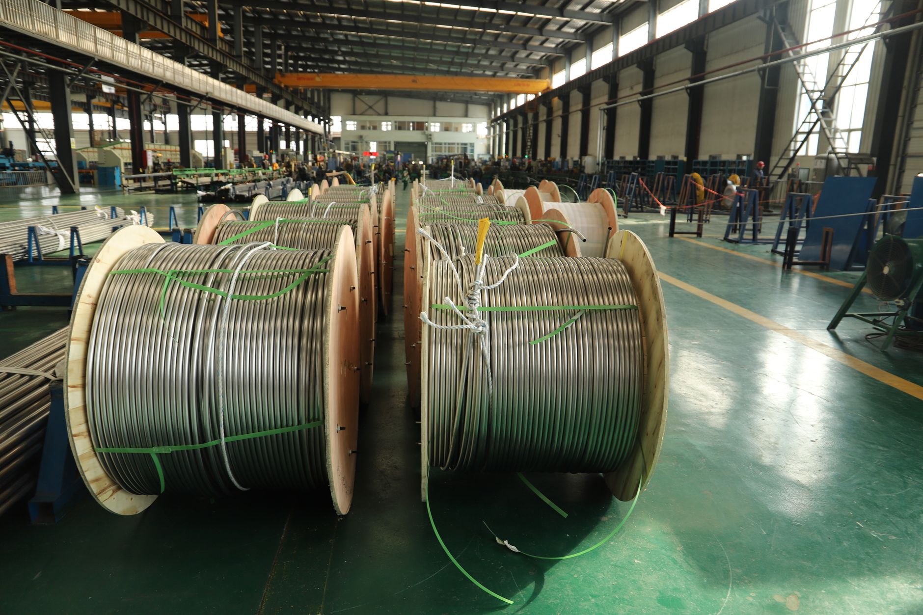 Large cable spools staged on a plant floor between production and storage areas.