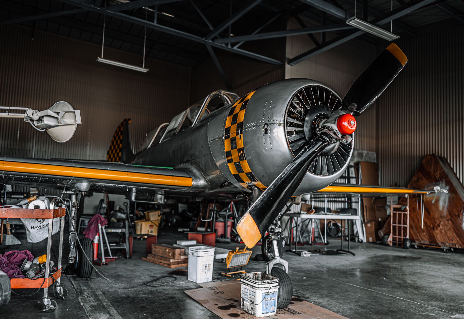 Wide view of an aircraft maintenance hangar with clear floor lanes, access stands, and support carts around a parked aircraft.
