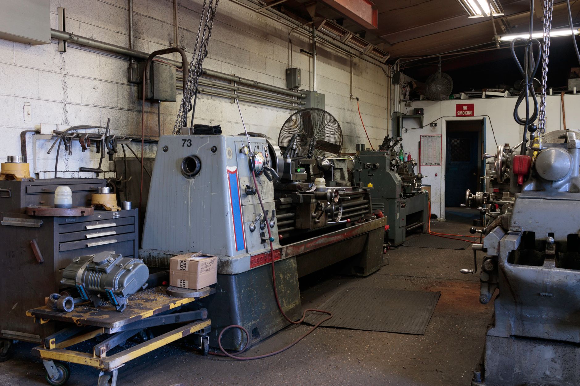 Wide view of a busy fabrication shop aisle between machines and work areas, matching the tool-crib-to-cell traffic described in the article.