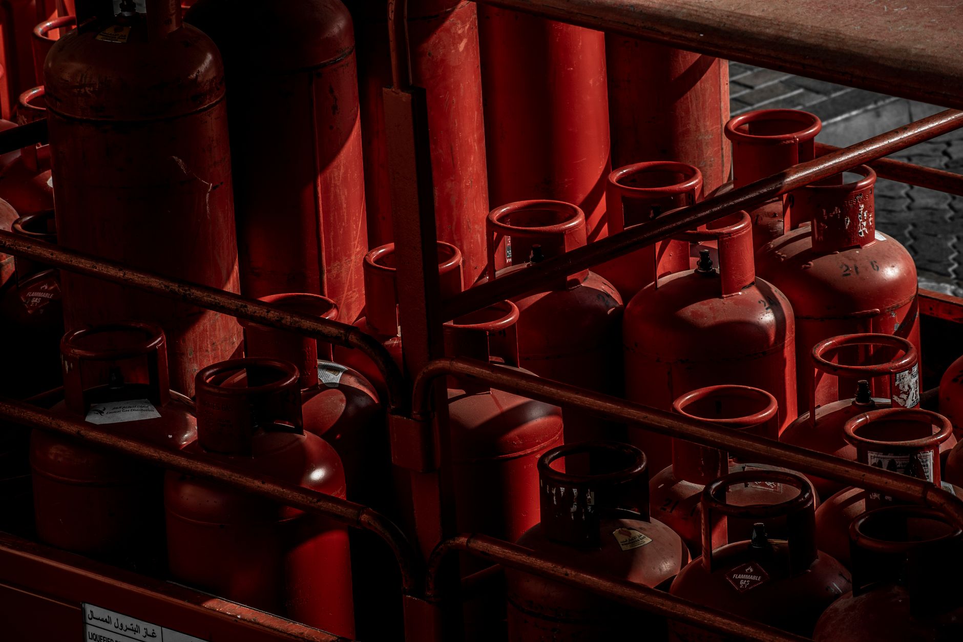 Chained welding gas cylinders stored upright on a cage shelf ready for exchange.