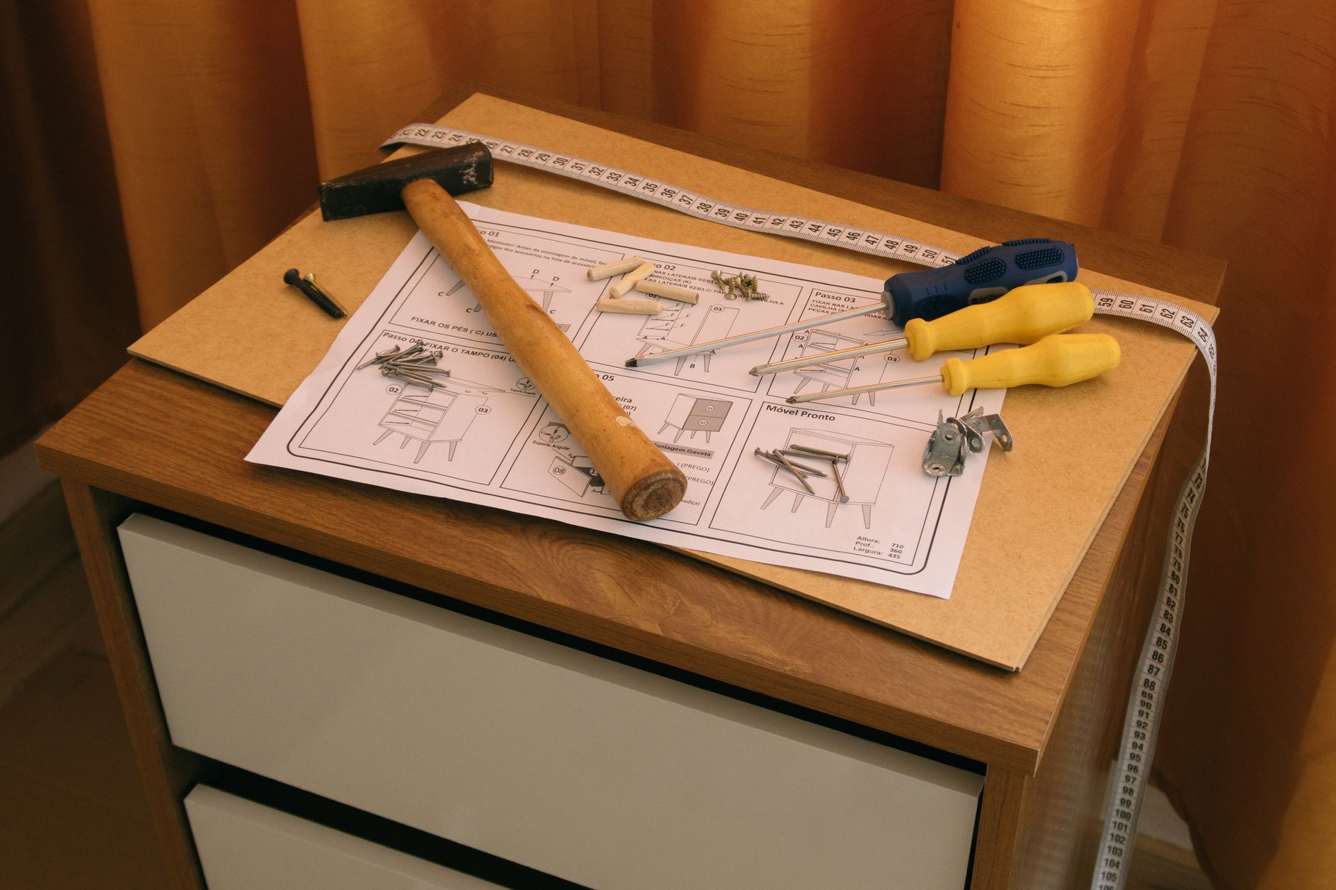 Furniture workers assemble cabinets while components and unfinished units wait at nearby stations.