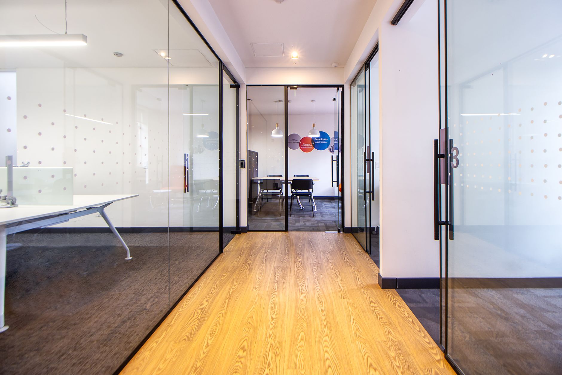 A clean hallway in a modern office showing the transition from carpeted tenant space to hard-surfaced common areas.