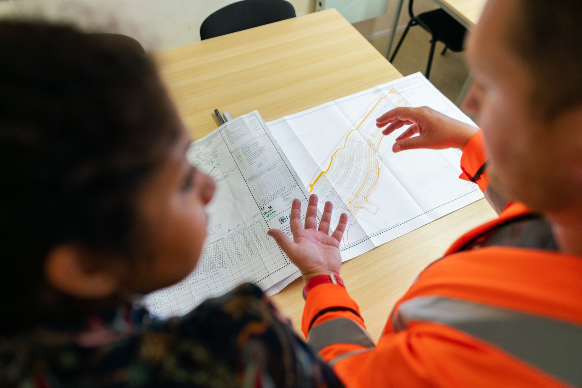 Two engineers collaborating over blueprints in a warehouse setting, planning an automation deployment.
