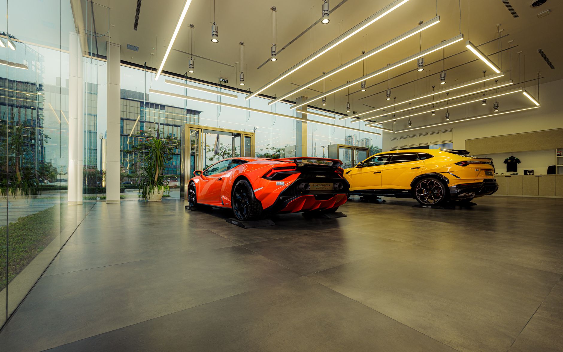 The highly polished, reflective floor of a modern car dealership showroom gleams under bright lights, with several luxury vehicles on display.