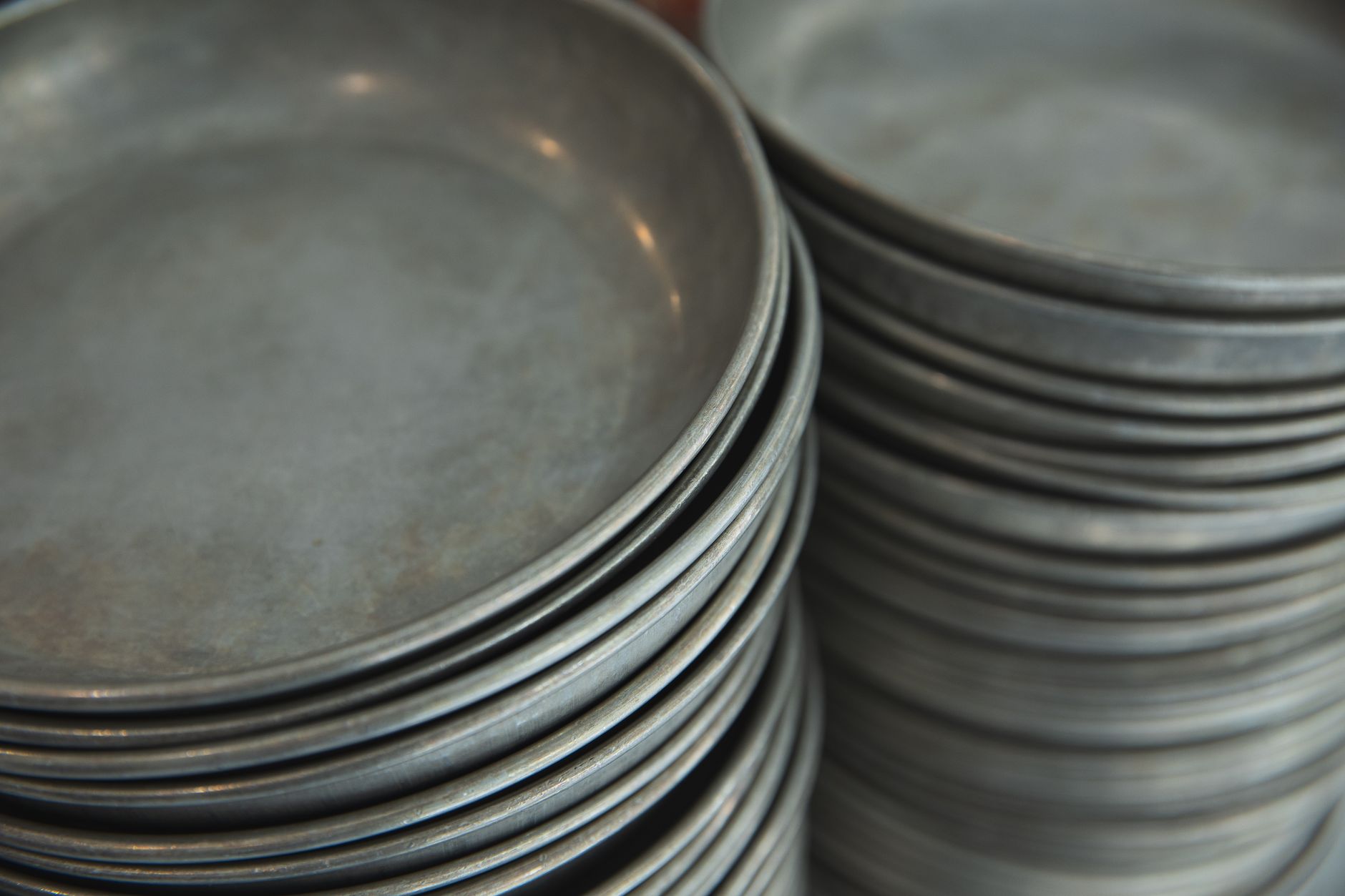 A stack of dirty dishes and trays waiting to be cleared, illustrating the bottleneck that manual bussing creates in a busy restaurant.