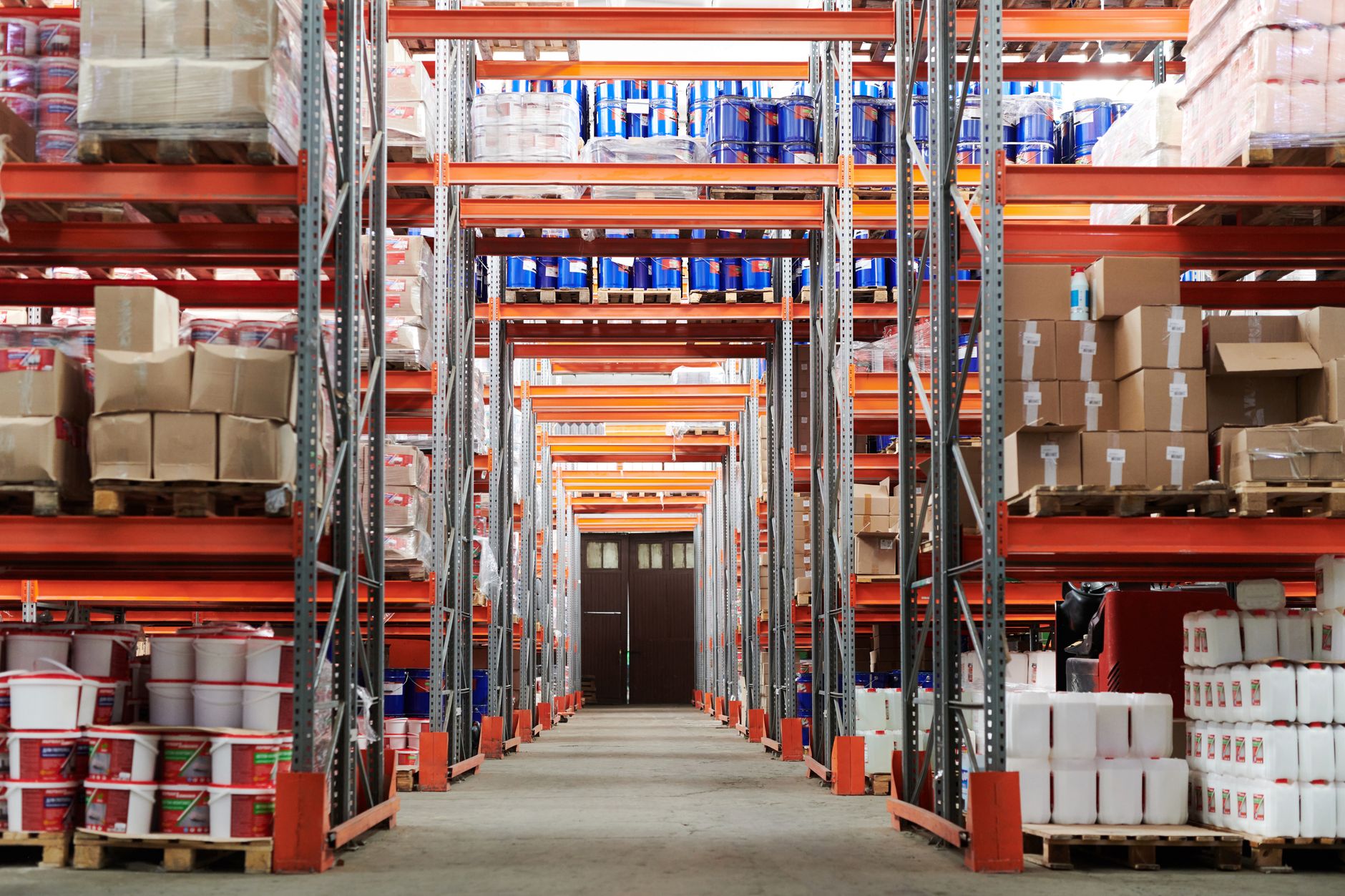 A wide view down an aisle of a clean and organized grocery store stockroom, with shelves neatly stacked with boxes.