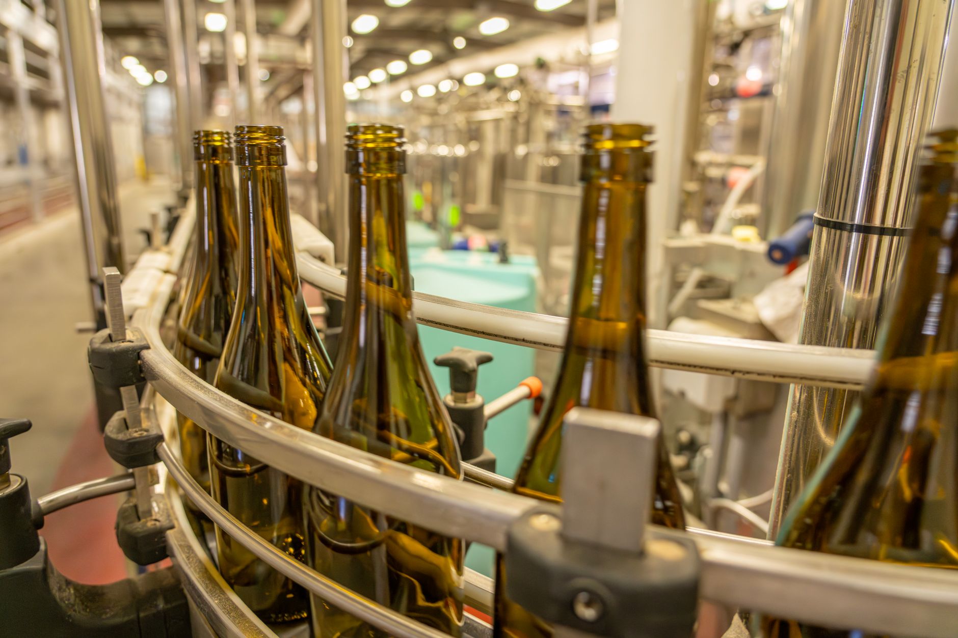 Glass bottles move in a blur down a fast-paced production line, illustrating the high-speed environment where automated QC is critical.