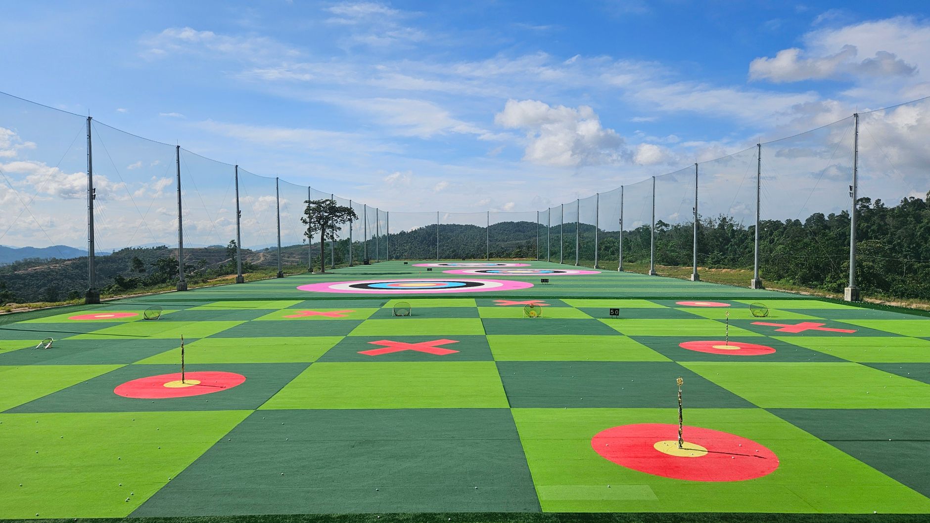 Tall netting poles along the edge of a golf practice range.