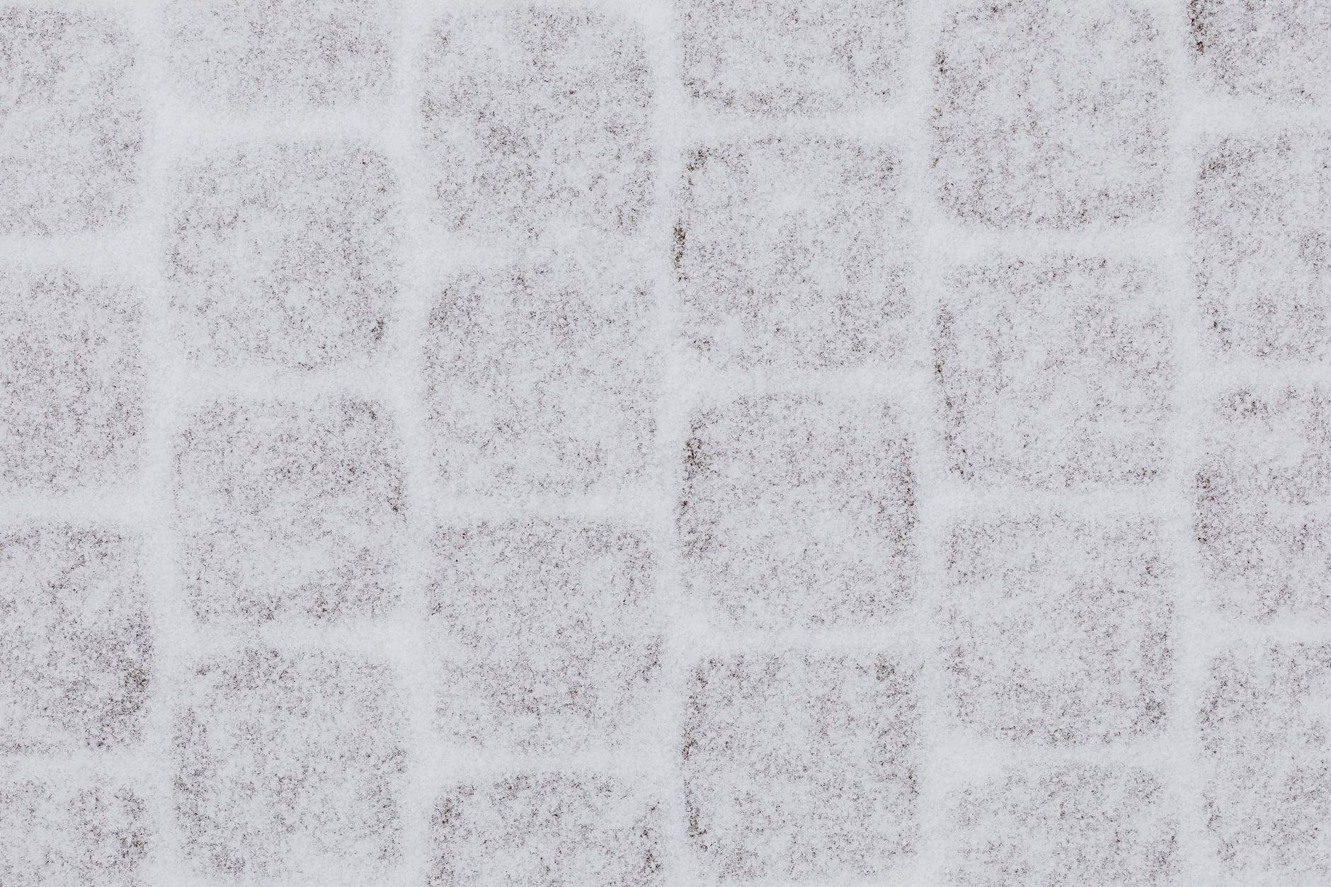 Icy sidewalk edge beside a building where deicing and shoveling are both in play.