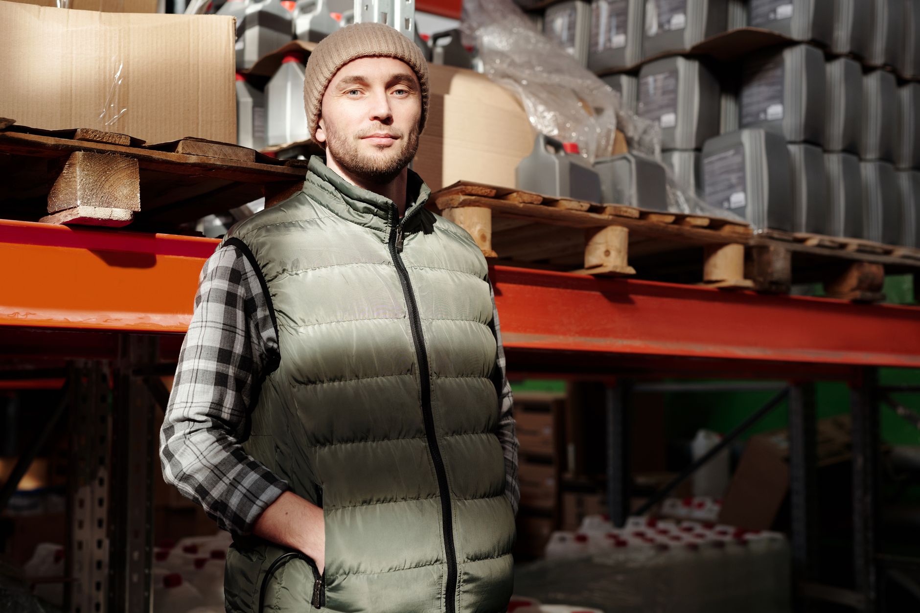 A warehouse worker checks labeled spare-parts bins in an organized multi-site inventory facility.