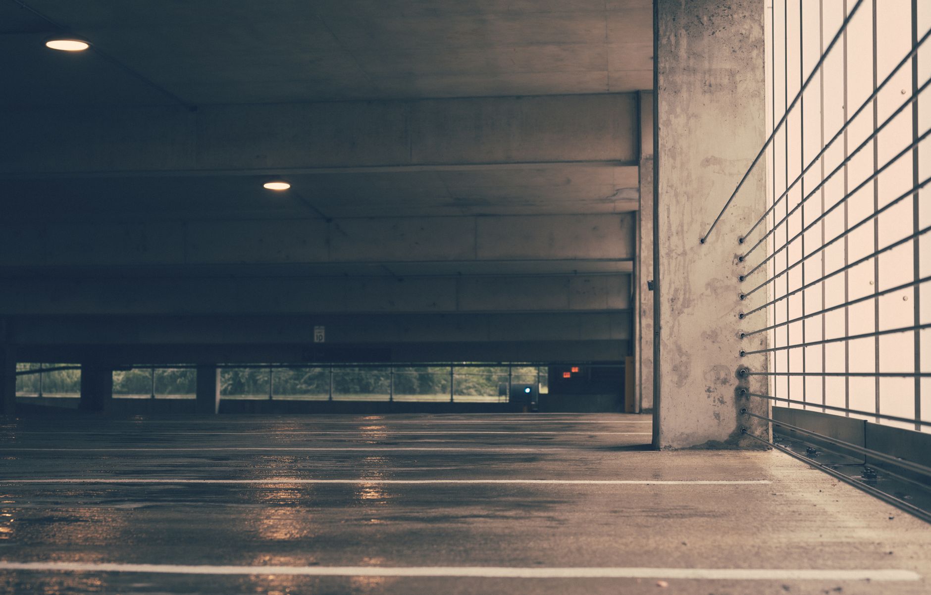 Rain blowing into an open-air level of a parking garage, highlighting the need for weatherproof security robots.