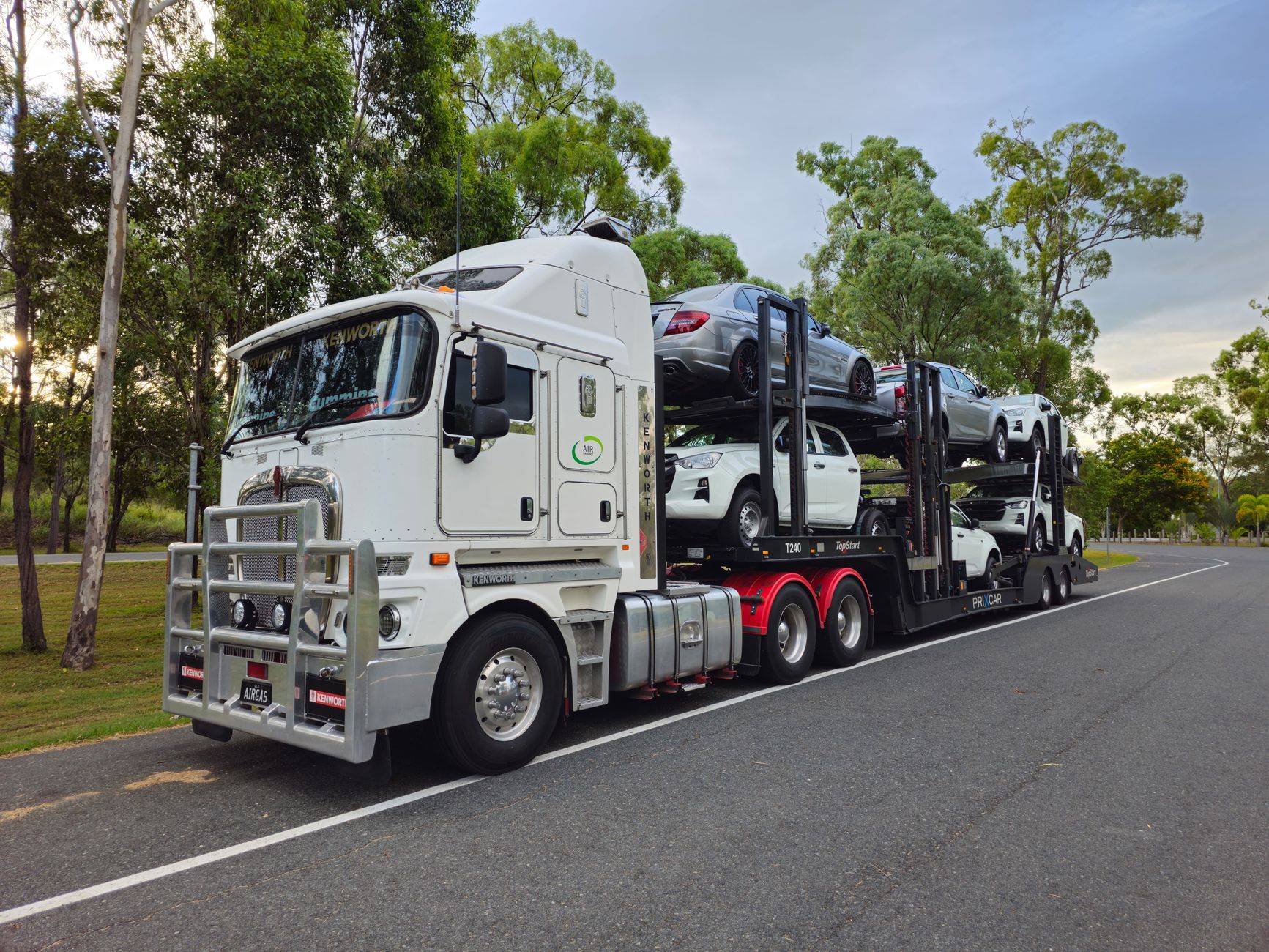 Workers loading vehicles onto a transporter amid the shifting traffic and staging activity of an auction yard.