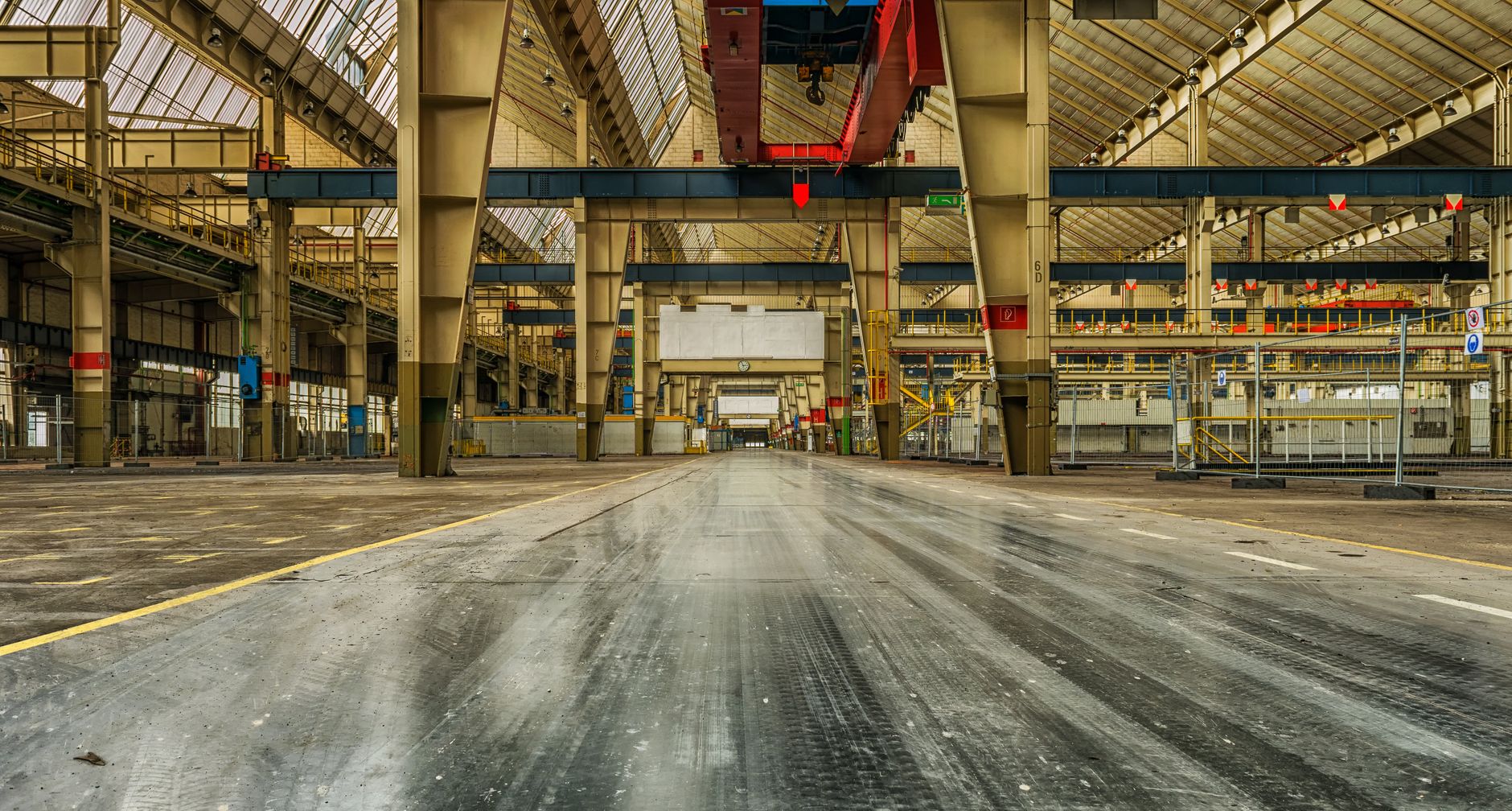 A wide-angle view of a vast, clean warehouse with polished concrete floors, illustrating an ideal environment for a fleet of robotic cleaners.