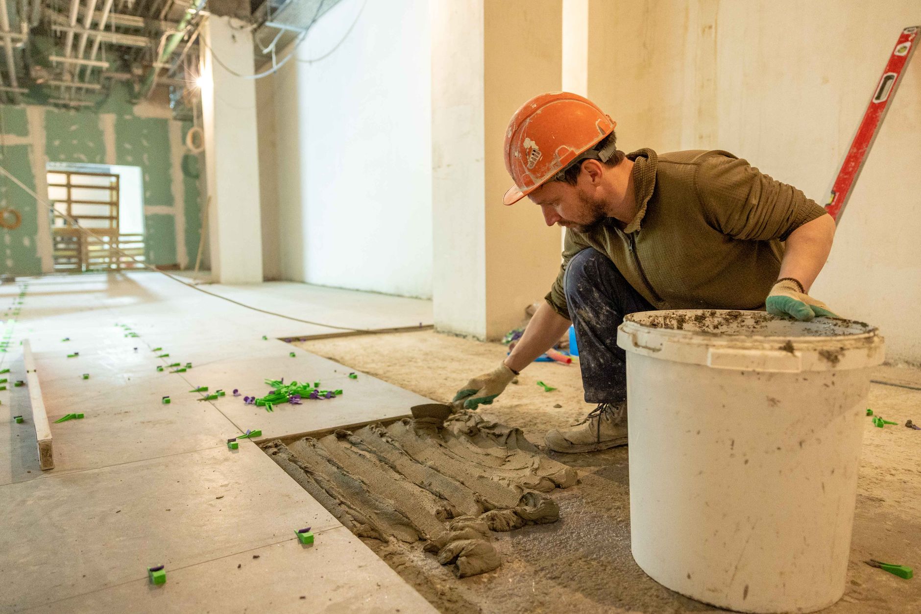 A technician lifting a modular raised-floor panel to inspect its support structure.