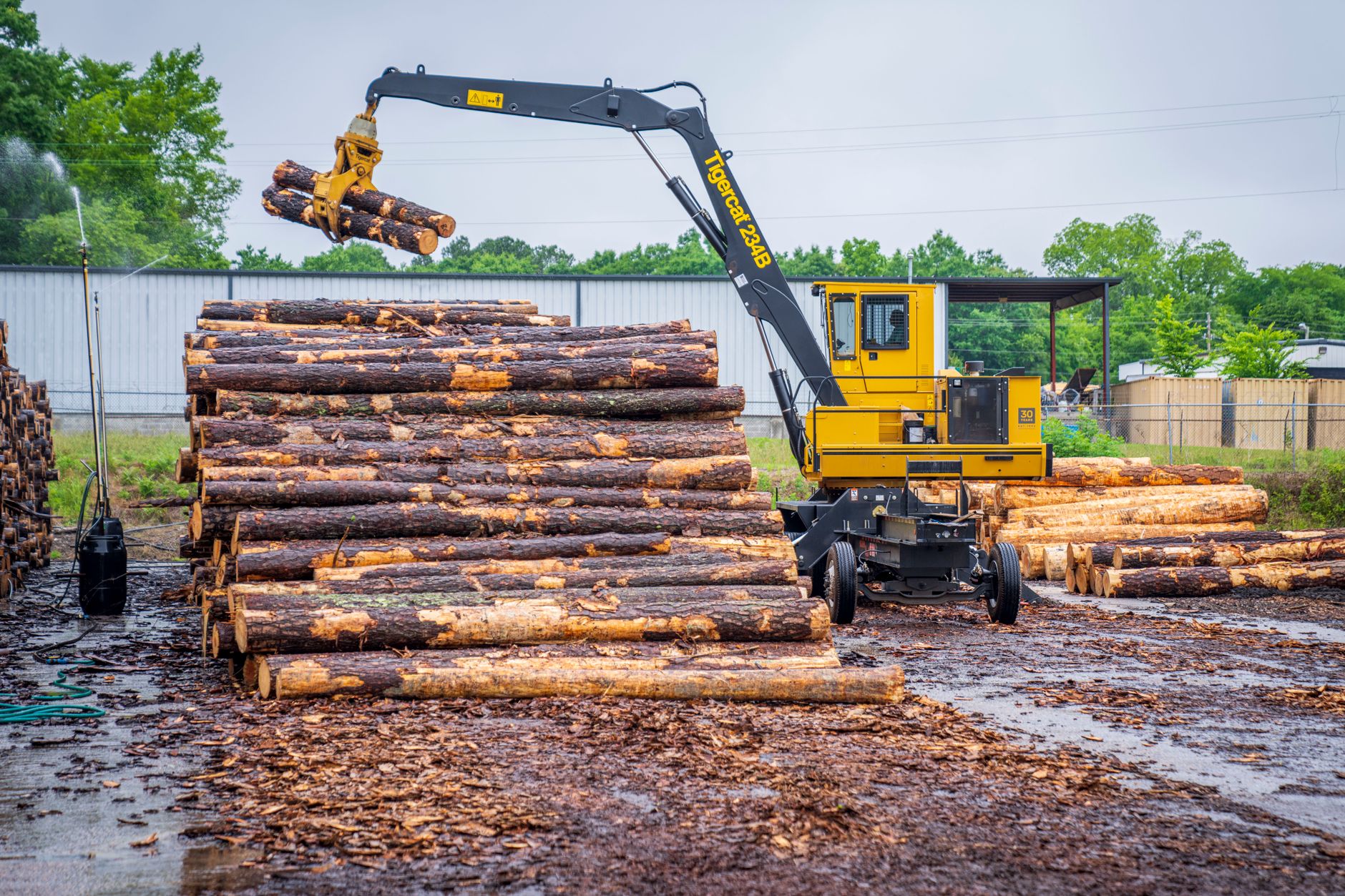 Workers load building materials in a busy supply yard with covered pickup areas and stacked inventory.