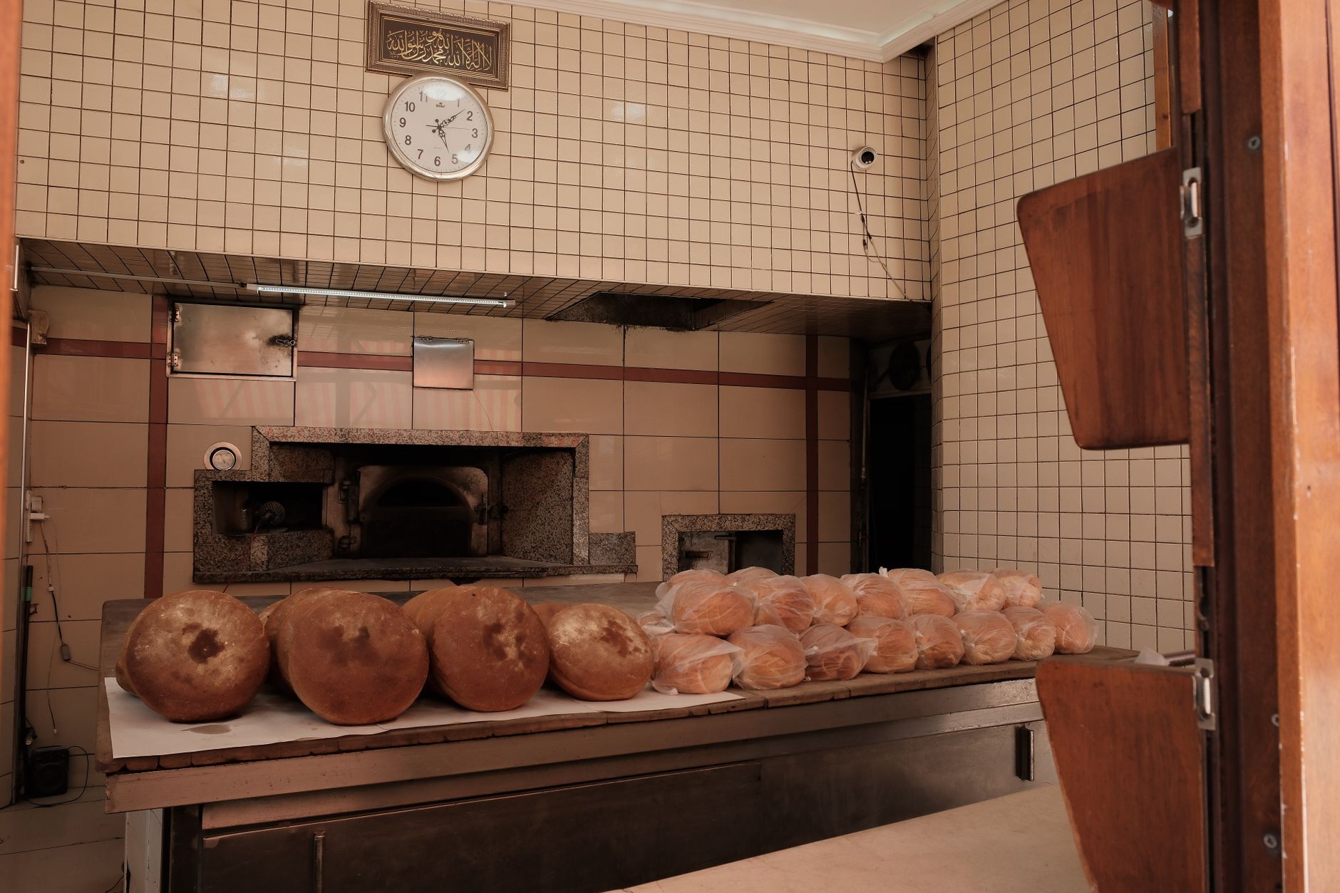 A spacious commercial bakery production floor with ovens, racks, and clear working aisles.