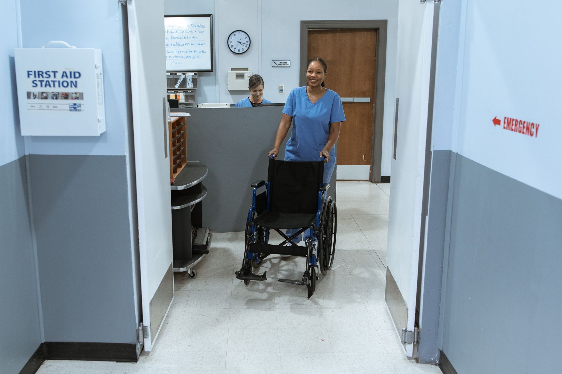 A staffed handoff point in a healthcare corridor near a nurse station, where supplies or trays could be received before resident service.