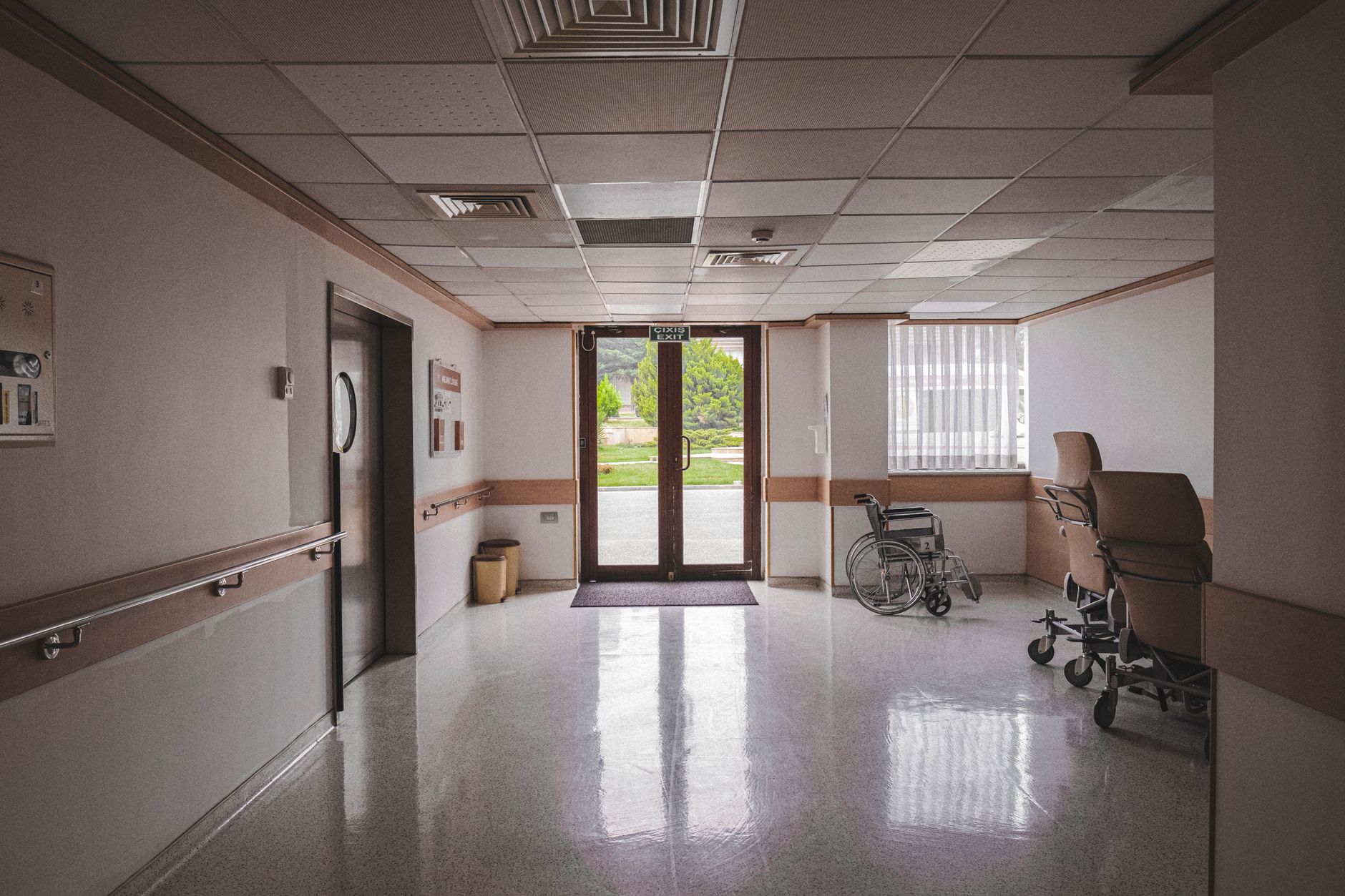 A wide care-facility hallway with wheelchair traffic and clear side space, showing why route width and staging matter.