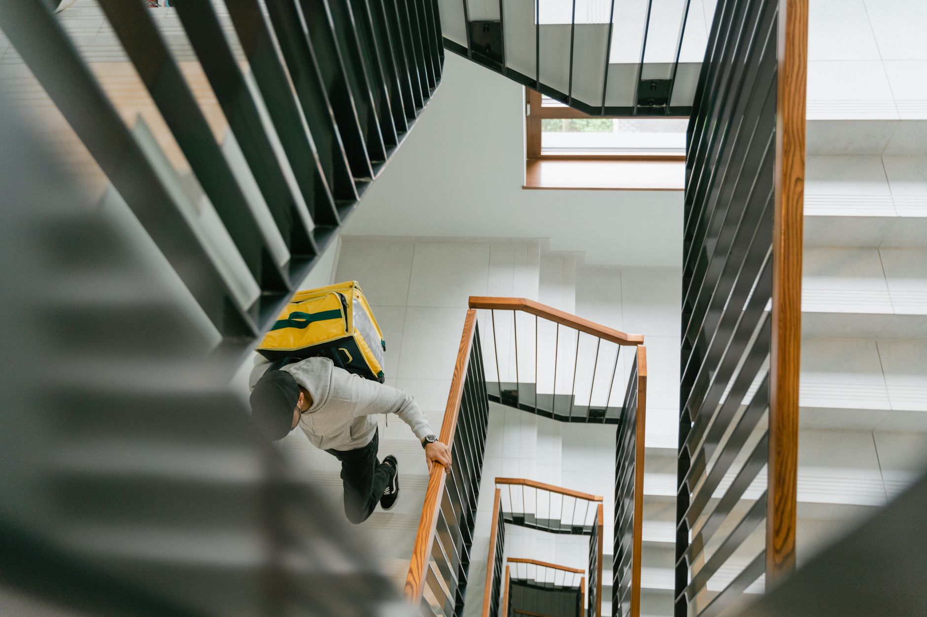 A delivery courier carries packages up outdoor steps during the final stretch to a customer.