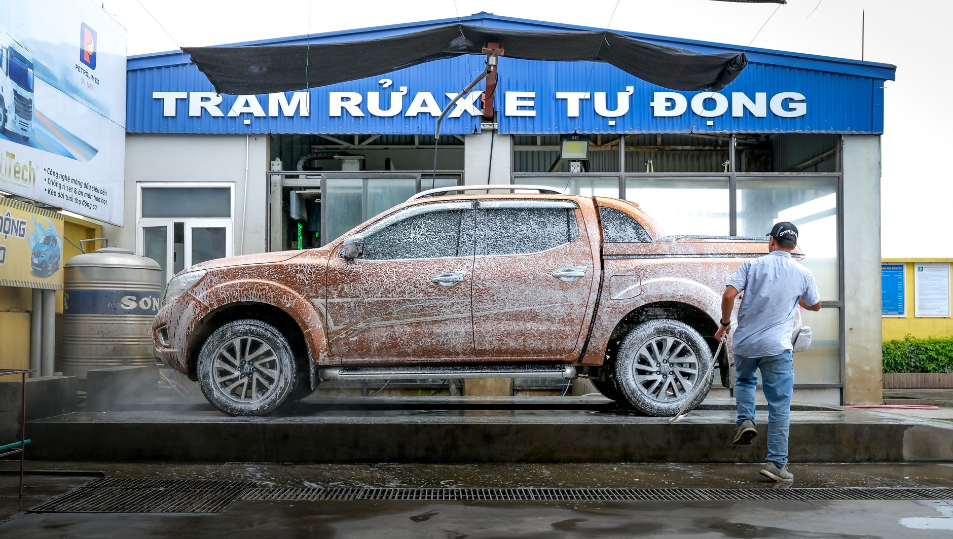 Wide view of a clean self-serve car wash site with vacuum lanes, open bays, and a tidy customer approach.
