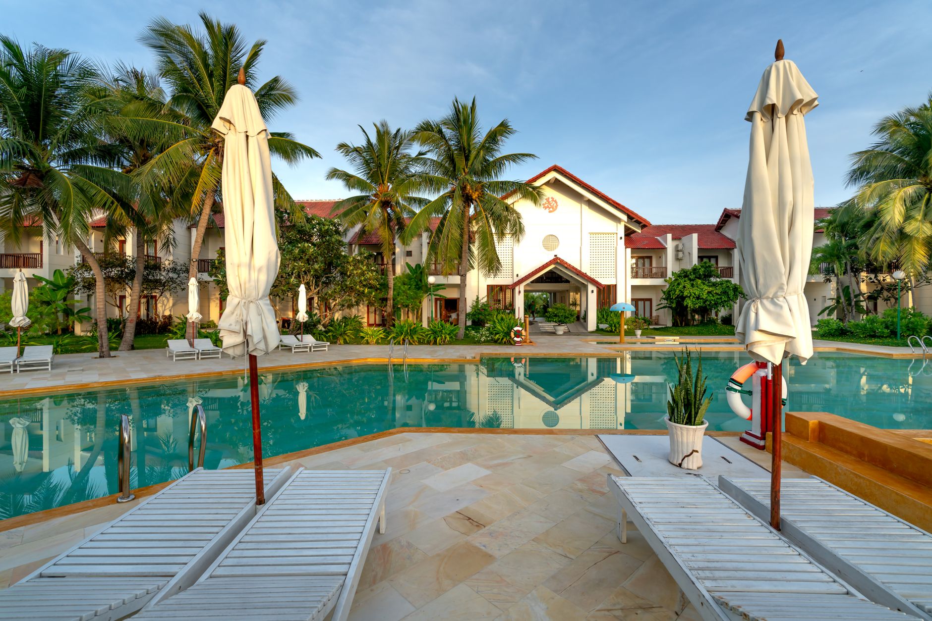 A beautiful resort with a large, clean pool under a clear blue sky, suggesting a premium guest experience.